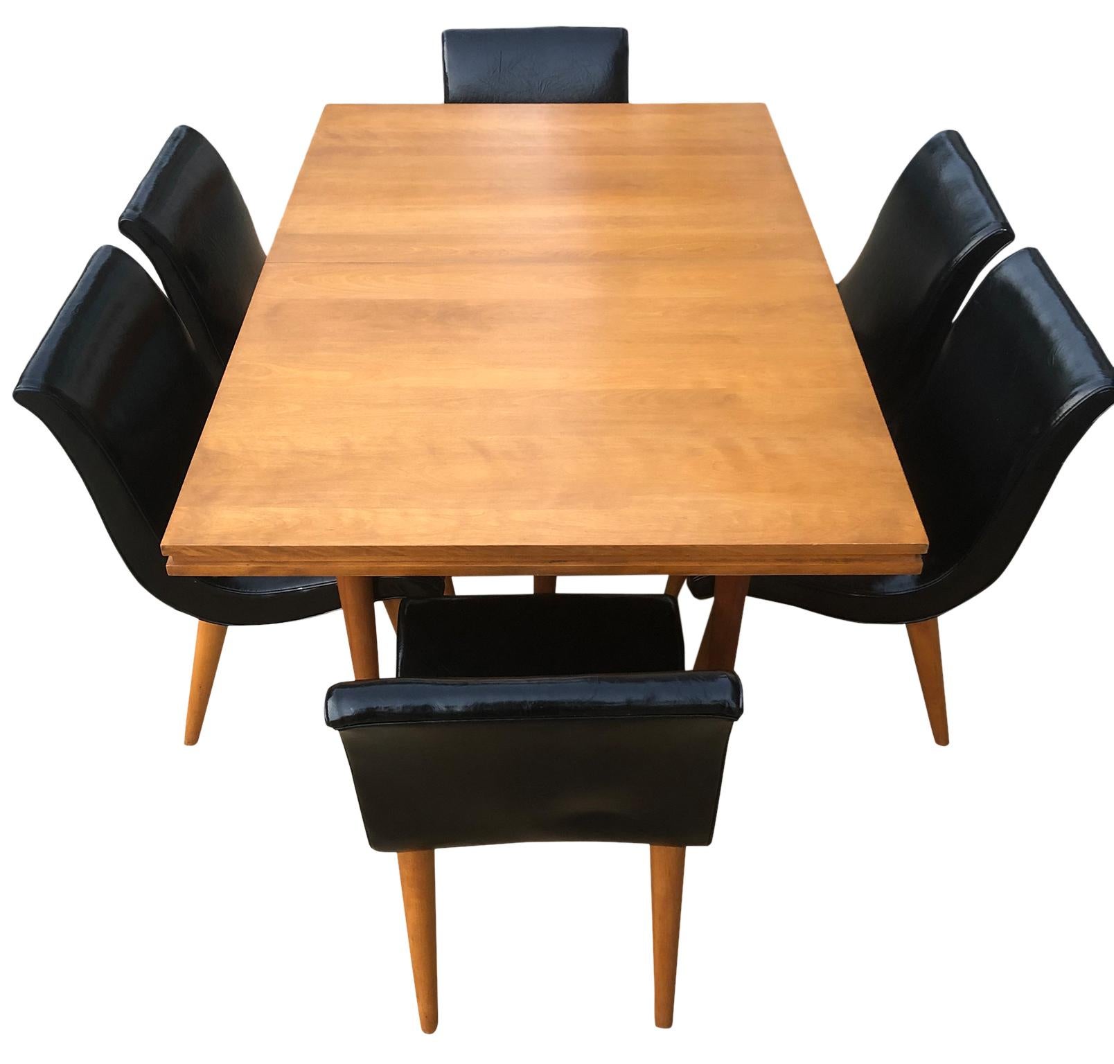 Beautiful early 1950s unique rare Russel Wright maple dining table set with 6 black armless chairs by Conant Ball, Great midcentury design. Very sturdy designed dining table #6007 with 6 tapered legs. Solid maple everything. (6) original black Vinyl