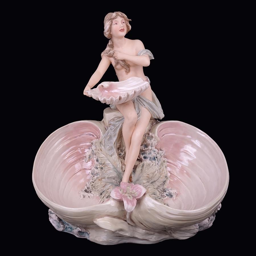 Offering this exceptionally high quality, signed Royal Dux (Bohemia) porcelain spill vase or vide-poche featuring a full-bodied maiden holding a shell figure with aquatic and floral motif in an Art Nouveau design. Vase has with an unusual iridescent