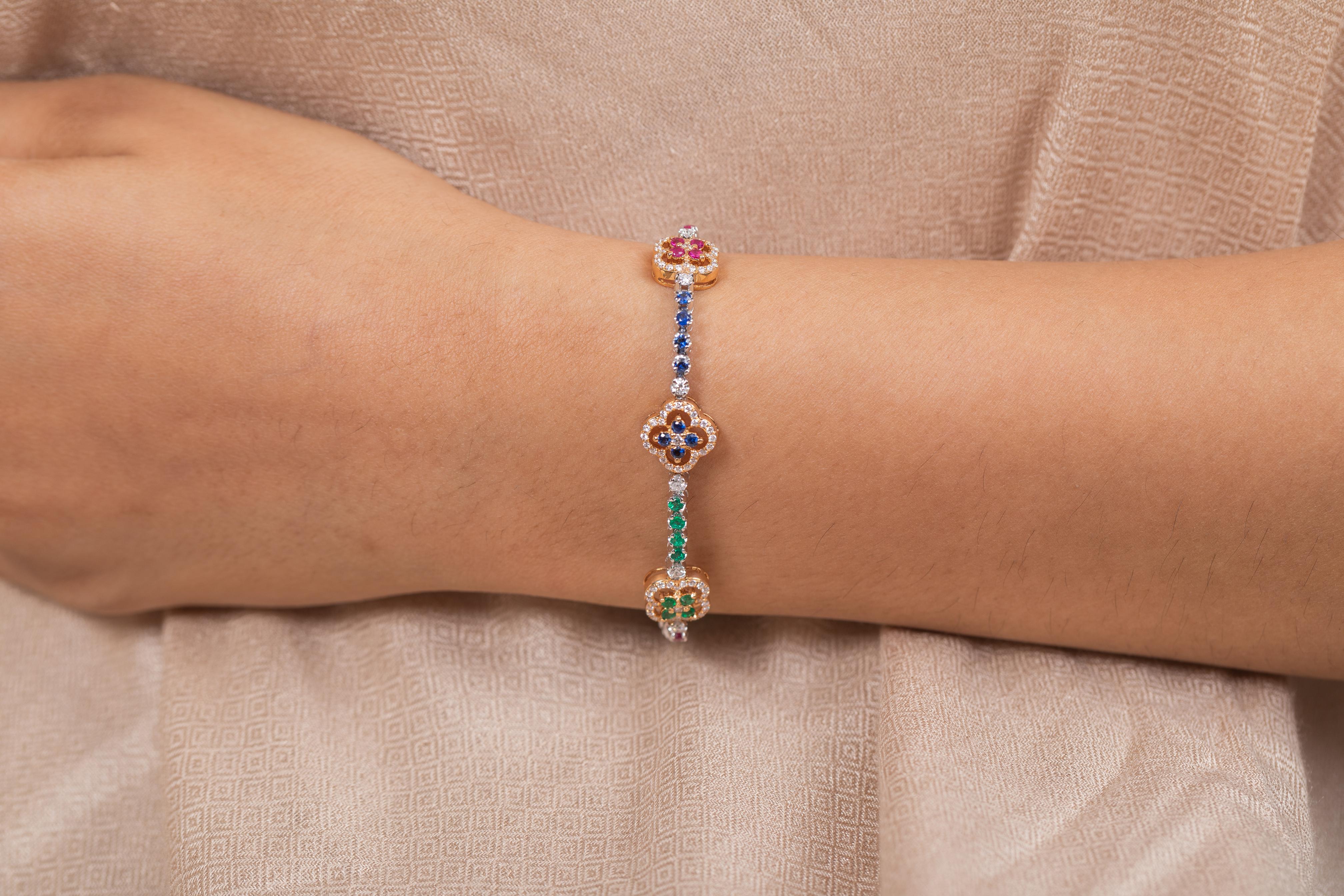Unique Diamond Ruby Sapphire Emerald Clover Charm Bracelet en or 18K met en valeur 48 rubis, émeraudes et saphirs naturels étincelants à l'infini pesant 2,29 carats avec 156 diamants de 1,36 carats. Il mesure 7 pouces de long. 
Le rubis améliore la