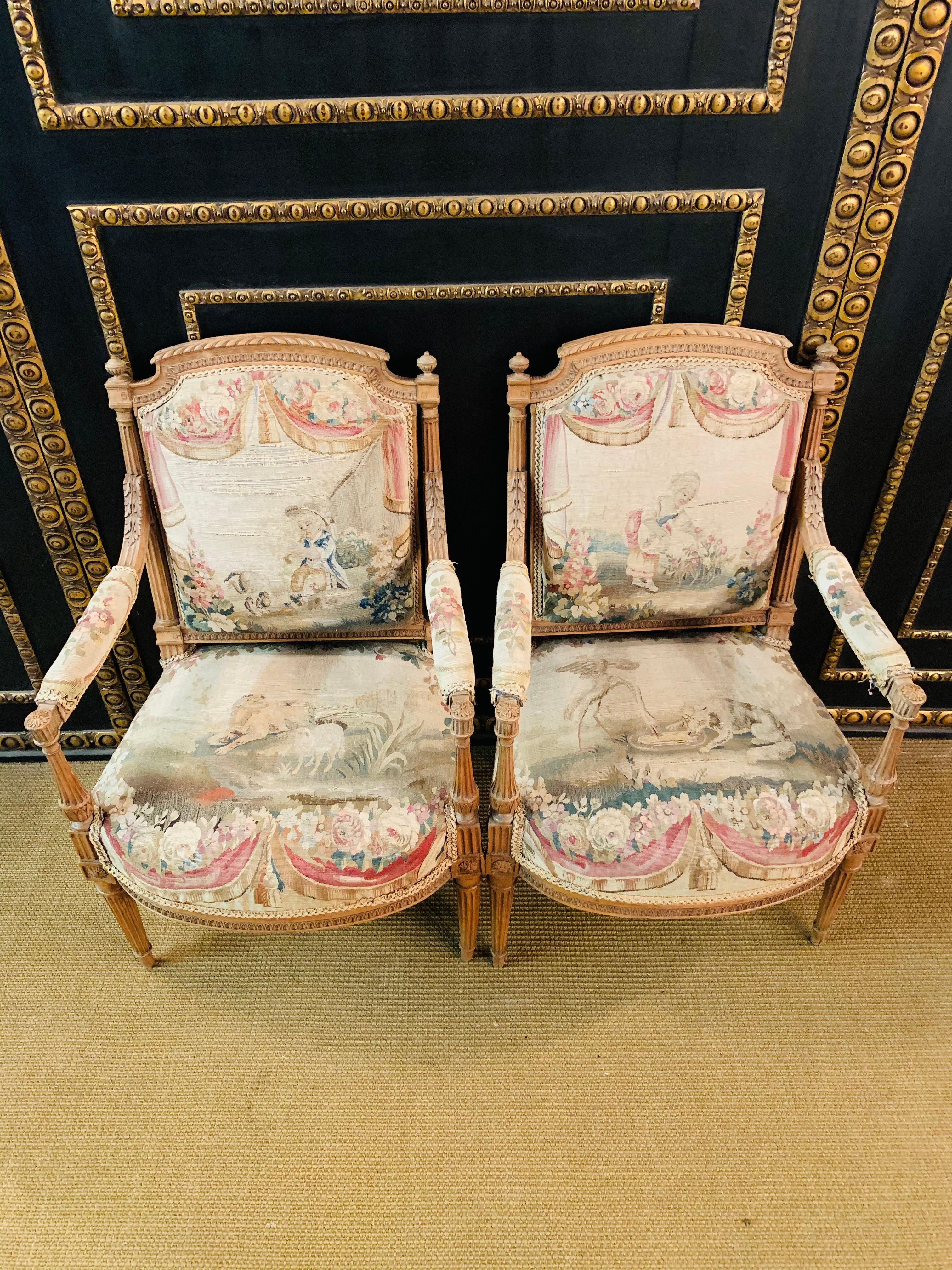 Pair of lounge chairs, Paris France 19th century, classical style, beech with solid oak, tapestry cover somewhat damaged.
 Gobelin fabric cover: Decorative floral bouquets and figures, Aubusson tapestry. 

 Dimensions in cm: 
Width 59cm
Depth