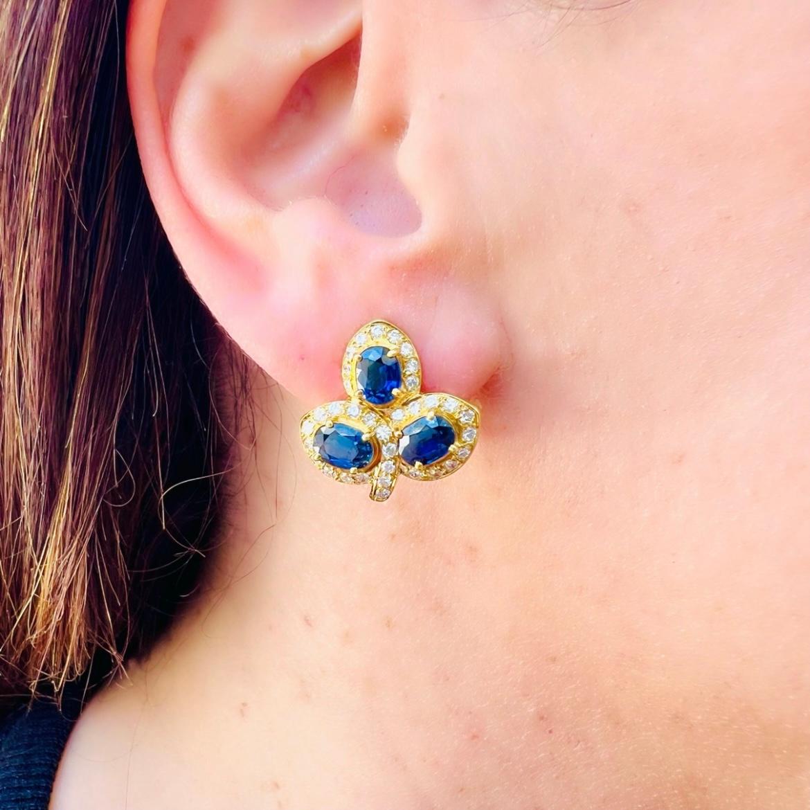 Circa 1970's, these floral designed sapphire and diamond earrings are every bit as in fashion now as when they were originally created. Featuring six sapphires (three in each ear) for approximately 3.96 carats total weight, each petal of this floral