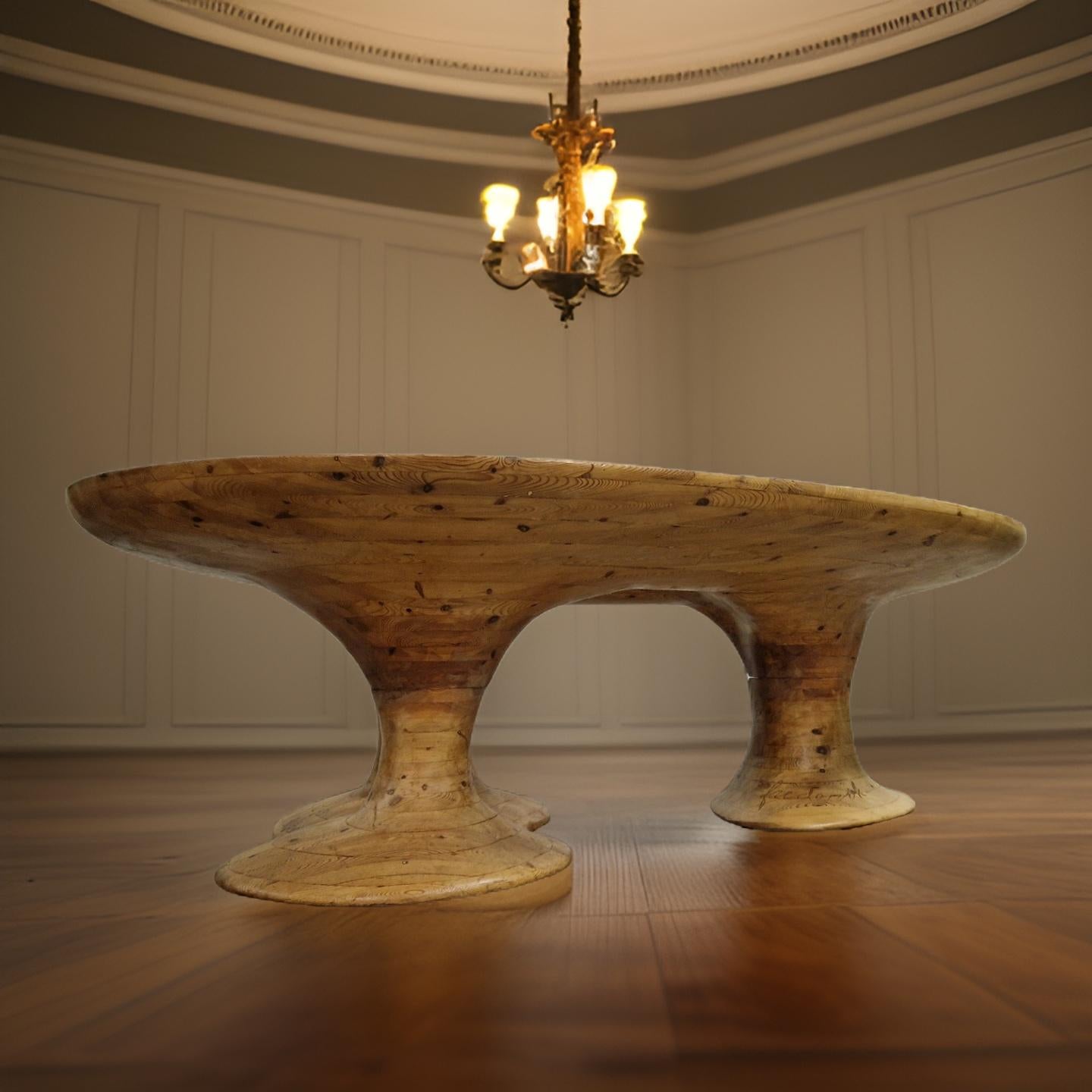 Unique hand crafted dining table. Sculpted from solid pine. The top resembles an artist palette while the three legs look like rock formations that have been sculpted by millennia of erosion. 
The table was sculpted by late visual artist Frederik