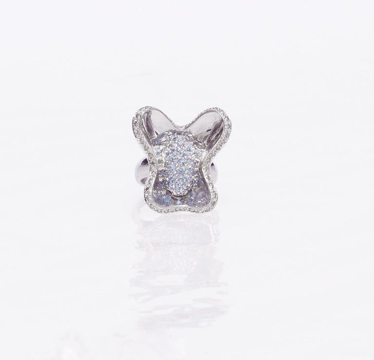 This unique ring is a jewel sculpture designed as a butterfly set in mirrored 18 Karat white gold wings surrounded by white diamonds and a central core with very light blue sapphires. Its brilliance will reflect in the wings in so many different