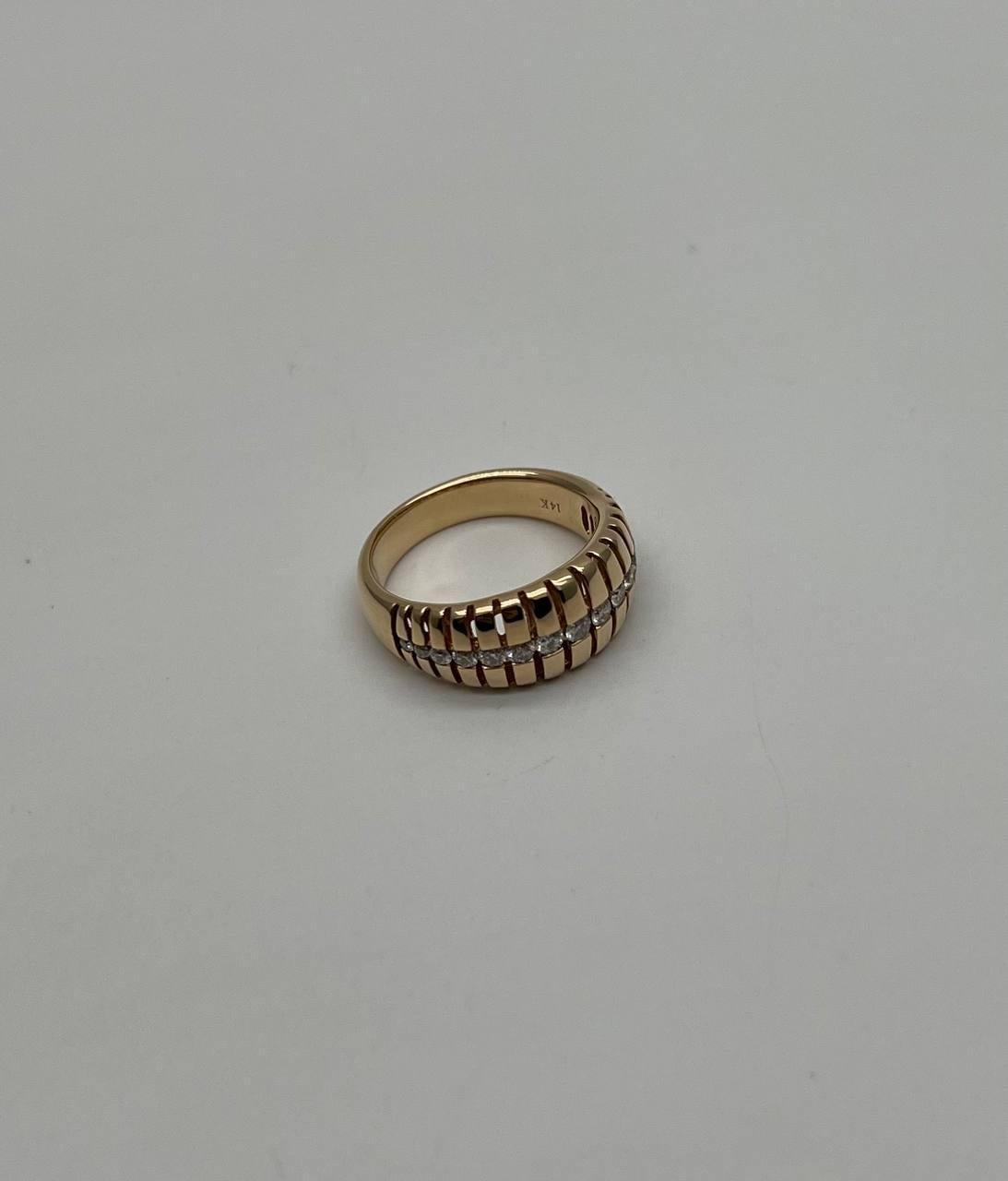 A sophisticated and elegant ring featuring a unique design with a series of vertical grooves encircling the band.
The ring is adorned with a central row of sparkling diamonds, adding a touch of brilliance and contrast to the textured surface.
This