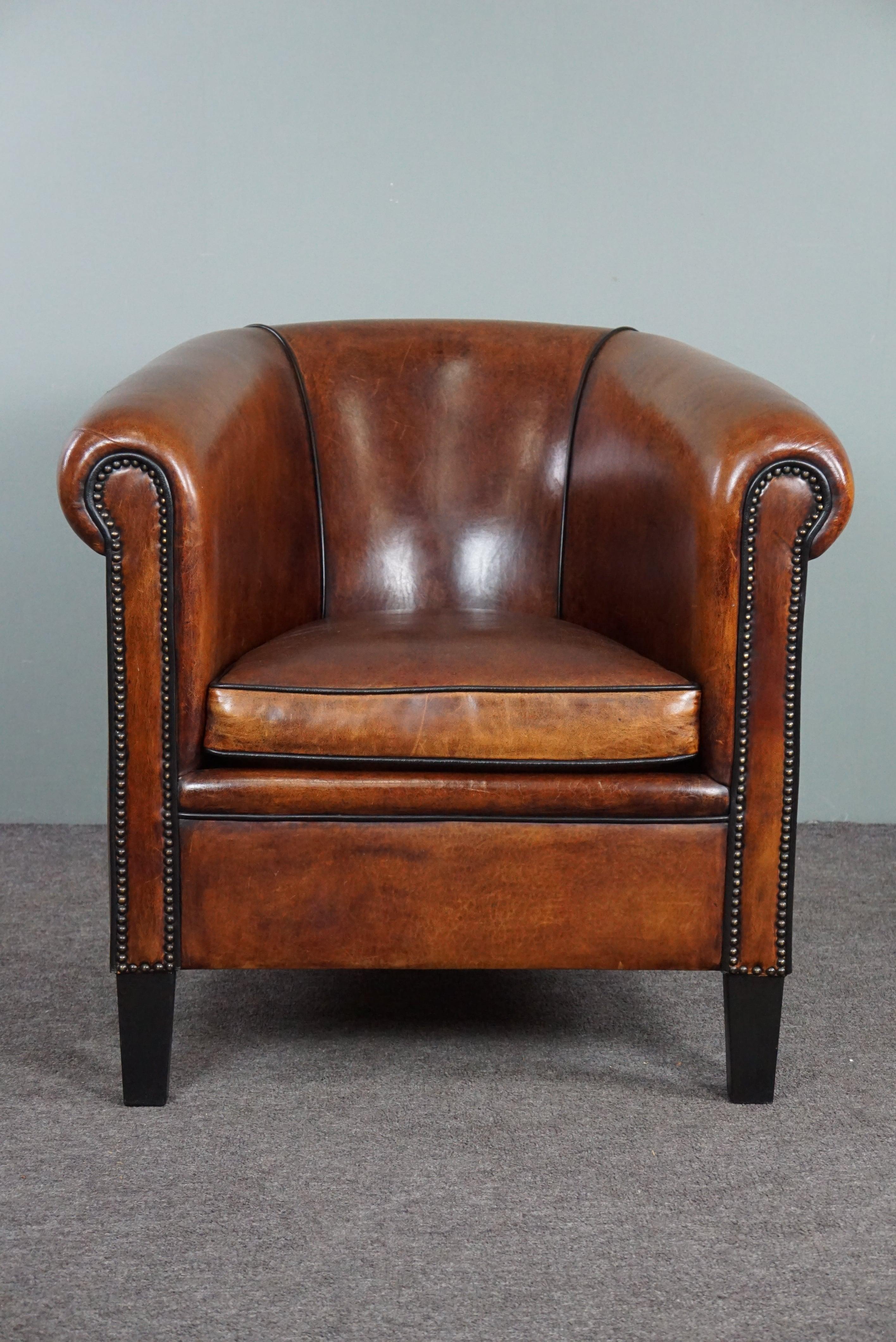 Offered is this very beautiful sheep leather club chair made with only top materials.

This custom-made sheep leather club chair is elegant because of the black piping in combination with the decorative nails and the amazing color. The depth of this