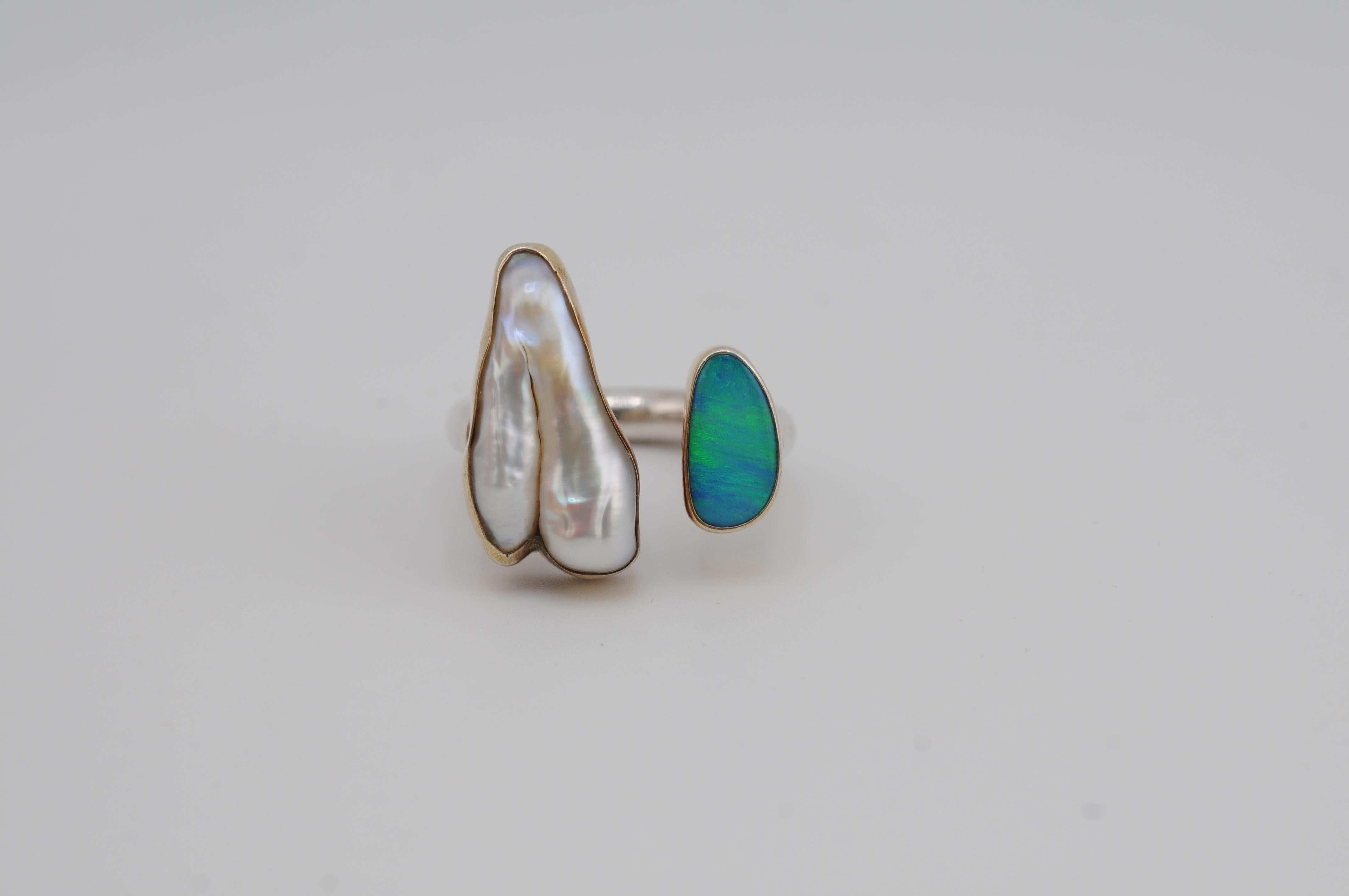 Un caratteristico anello in argento sterling con un'opale naturale e una perla d'acqua dolce keshi. Sottili elementi dorati conferiscono calore ed eleganza al design. Un pezzo senza tempo e di carattere, in equilibrio tra bellezza grezza e