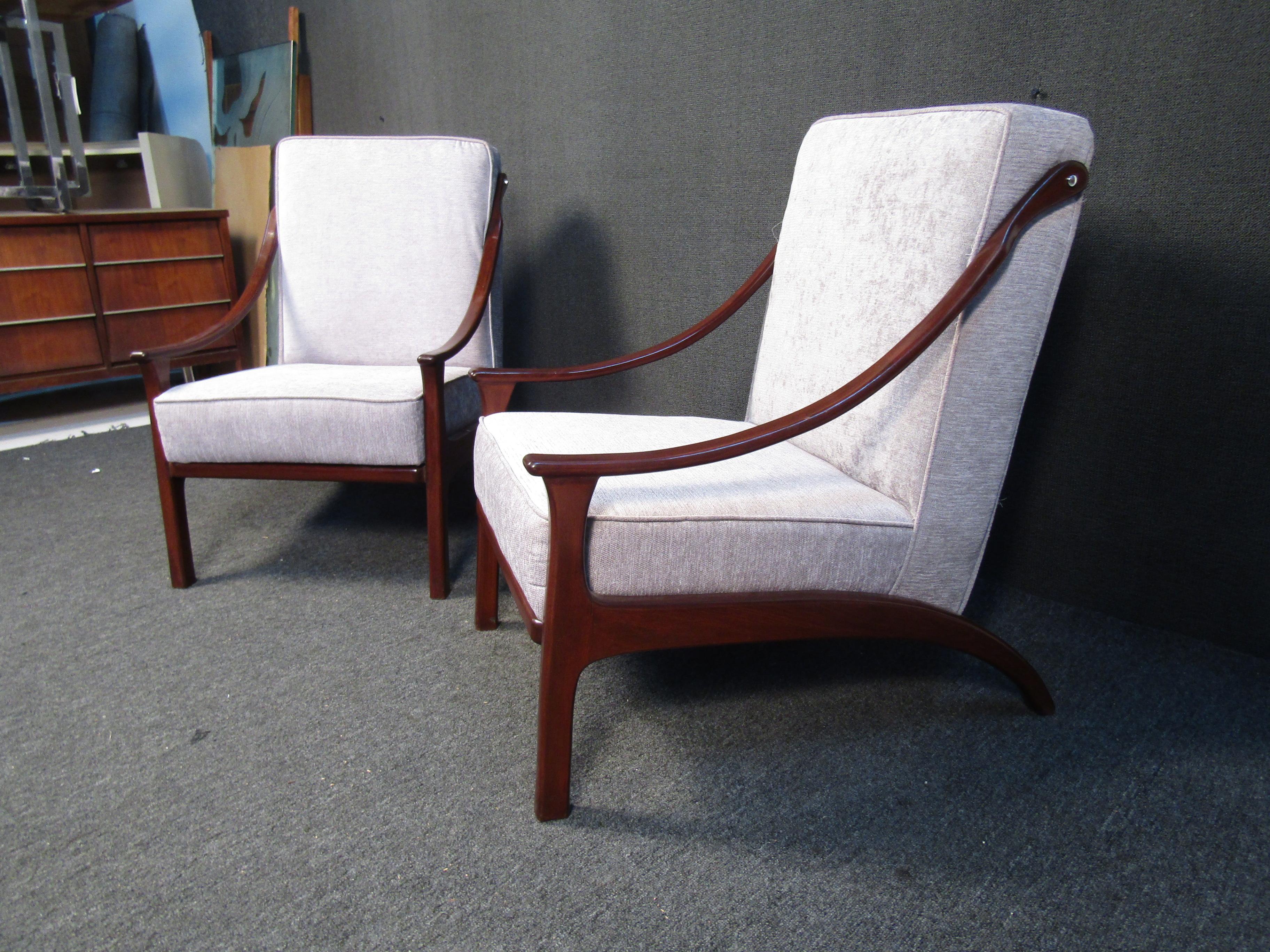 These mid-century style chairs feature a light colored upholstery and sloped wood legs/arms. A stylish pair, these chair will make a great accent to any living space. Please confirm item location (NJ or NY).