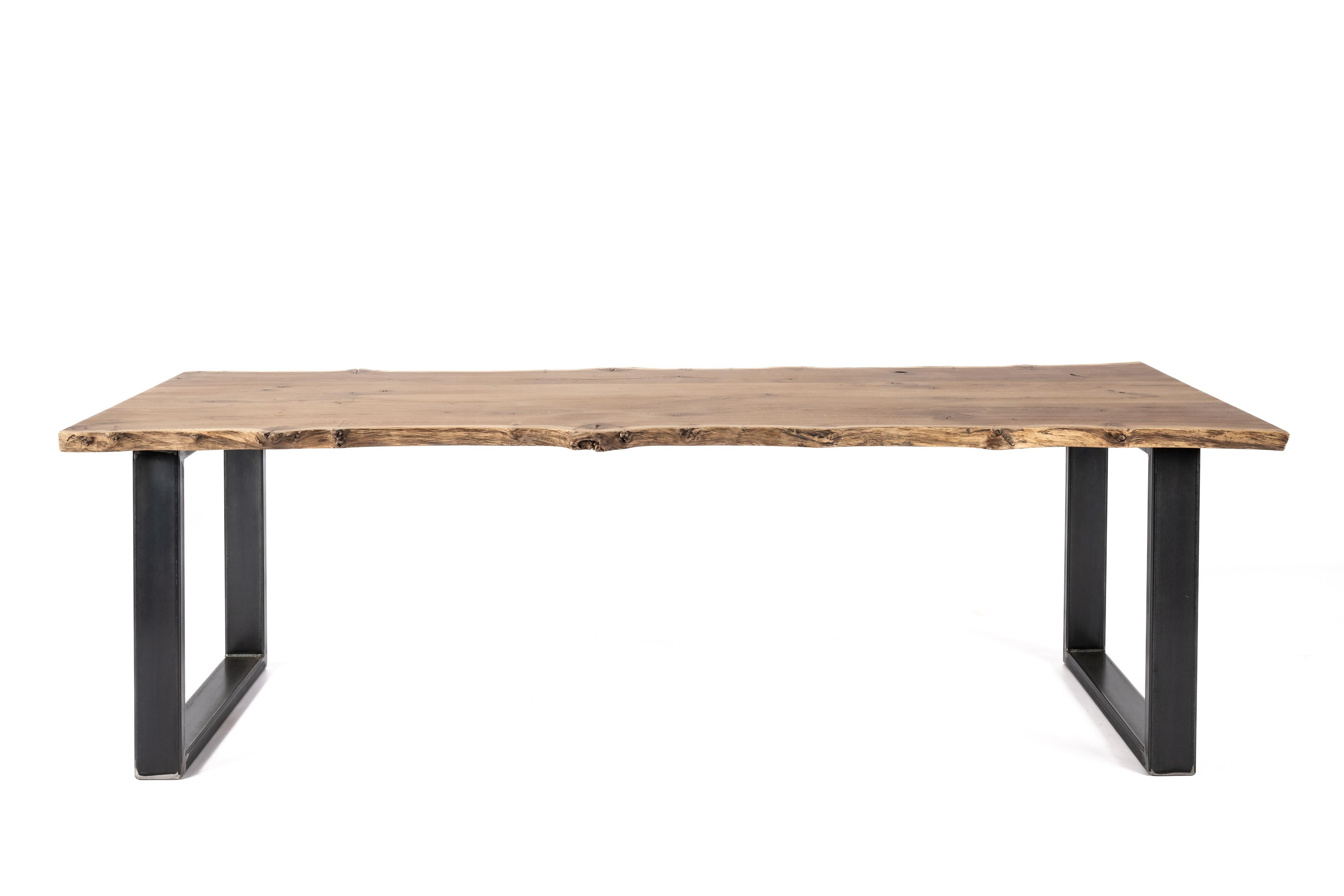 On offer here is a unique live edge solid aged oak dining table with a matte natural finish. Handcrafted from premium aged oak sourced from the lush forests of Northeastern France, this table boasts a unique charm that sets it apart. This unique