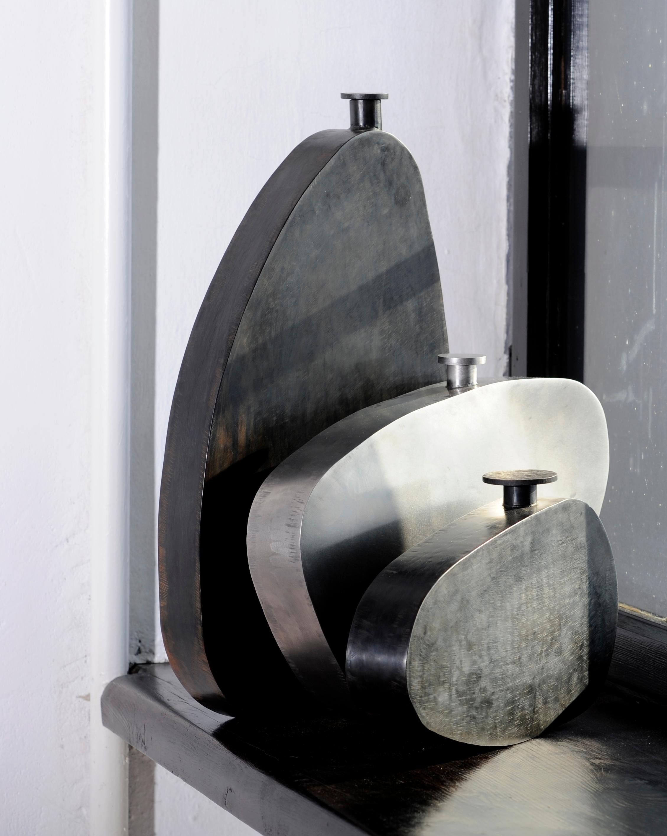 Unique steel bottles, clouds trio, signed by Lukas Friedrich.
1. Steel bottle “small cloud” - 37 x 6 H 21 cm.
2. Steel bottle “medium cloud” - 36 x 6 H 30 cm.
3. Steel bottle “large cloud” - 30 x 7 H 51 cm.
Finish: black patina on steel,