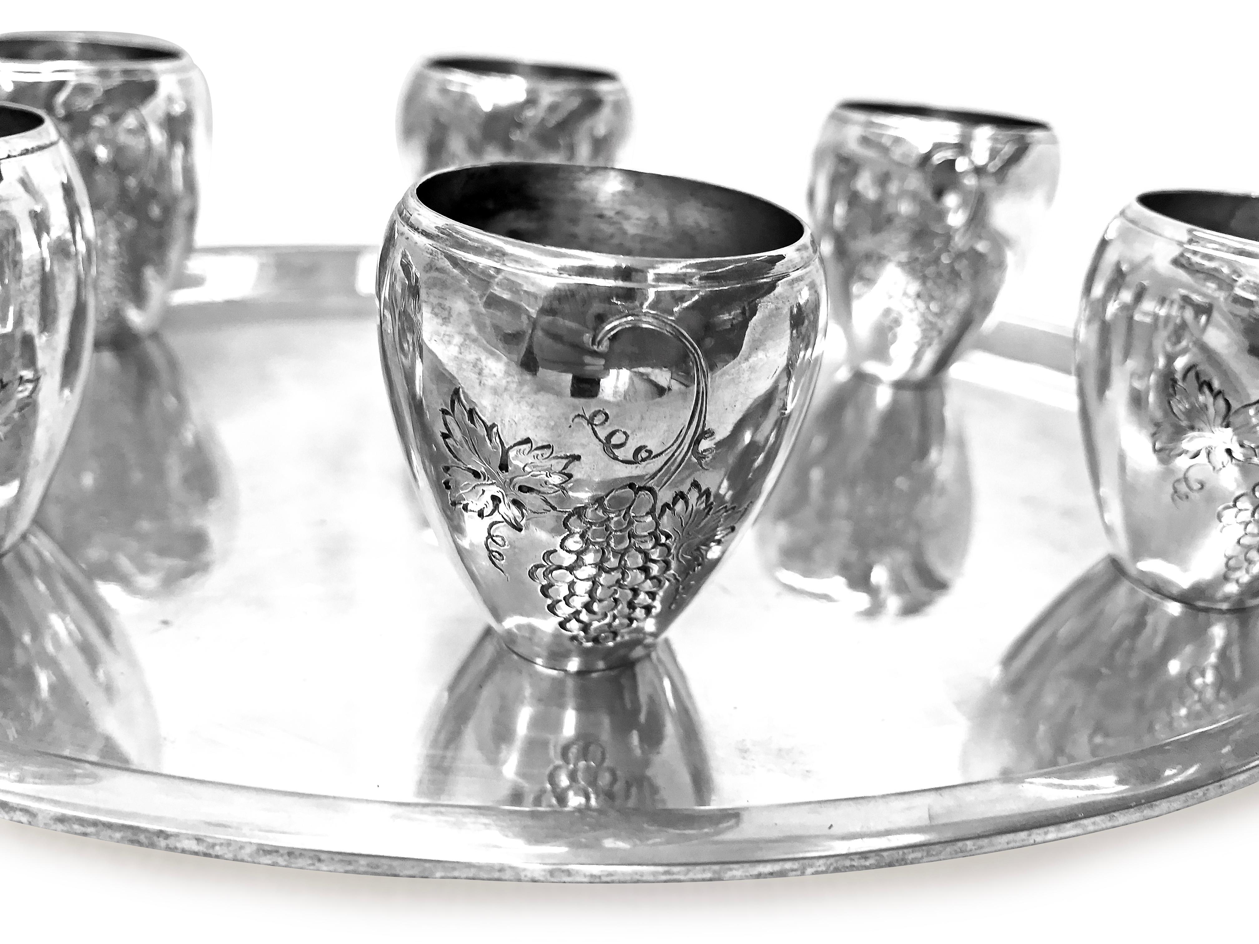 This unique piece of sterling silver set is including 6 beautiful shape cups with very delicate grape engraving design on them . They have like an egg shape with design around them . The tray is simple and pretty with oval shape. There is a BK stamp