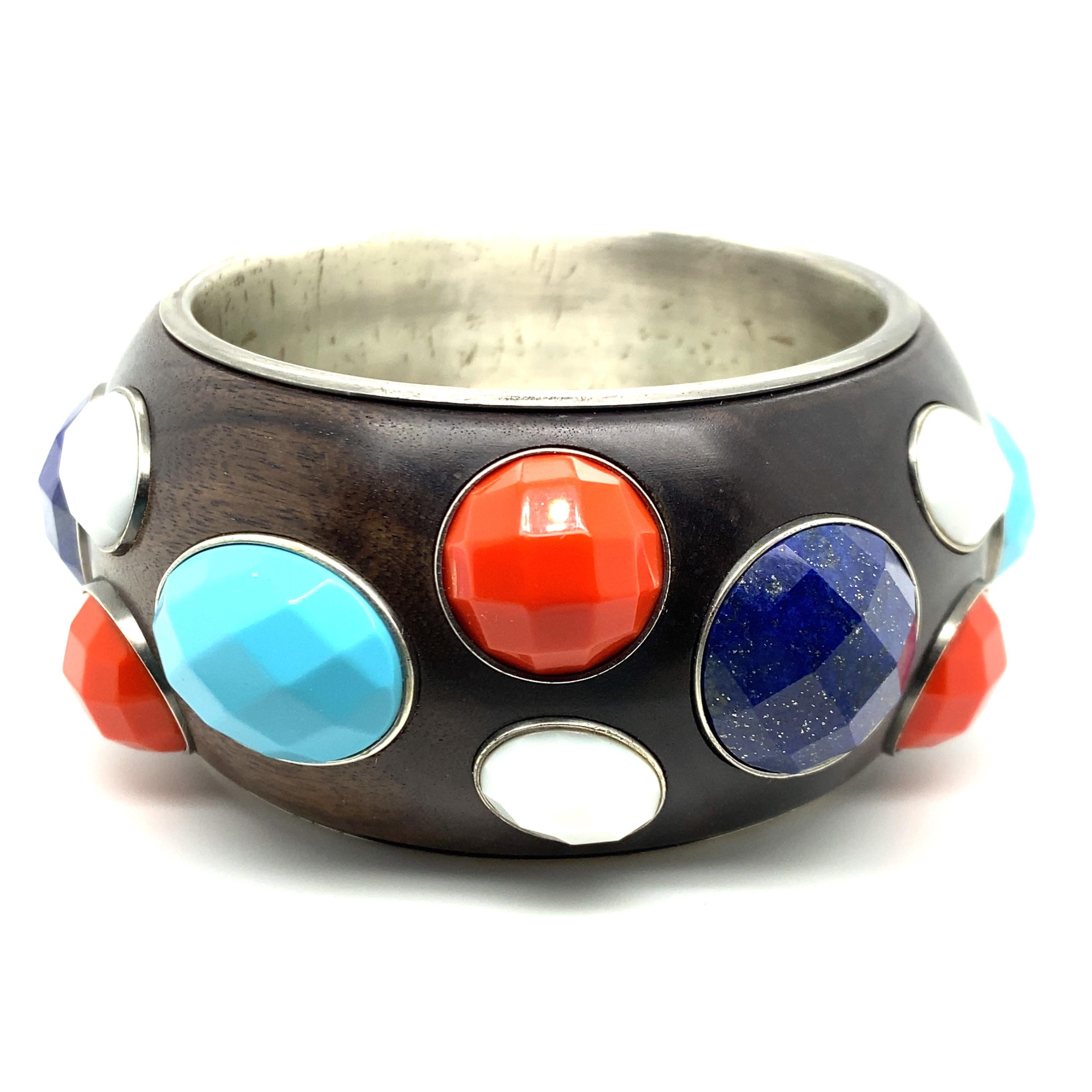 A Sterling Silver, Wood and Glass Bangle Bracelet by Bottega Veneta,
Consisting of a sterling bangle bracelet with inlaid wood and oval shape checkerboard cut synthetic stones in turquoise, red, blue and white. Resembling turquoise, red and white