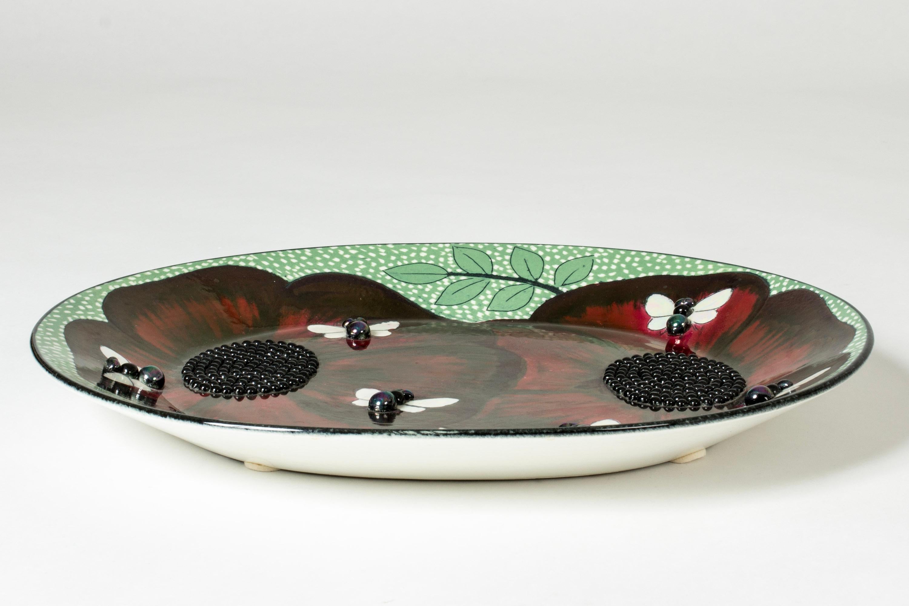 Amazing, unique stoneware platter by Birger Kaipiainen. Beautiful composition with deep red poppy flowers with seeds in relief in the center and butteflies scattered on the petals.

Birger Kaipiainen was Finland’s foremost ceramic artist of the