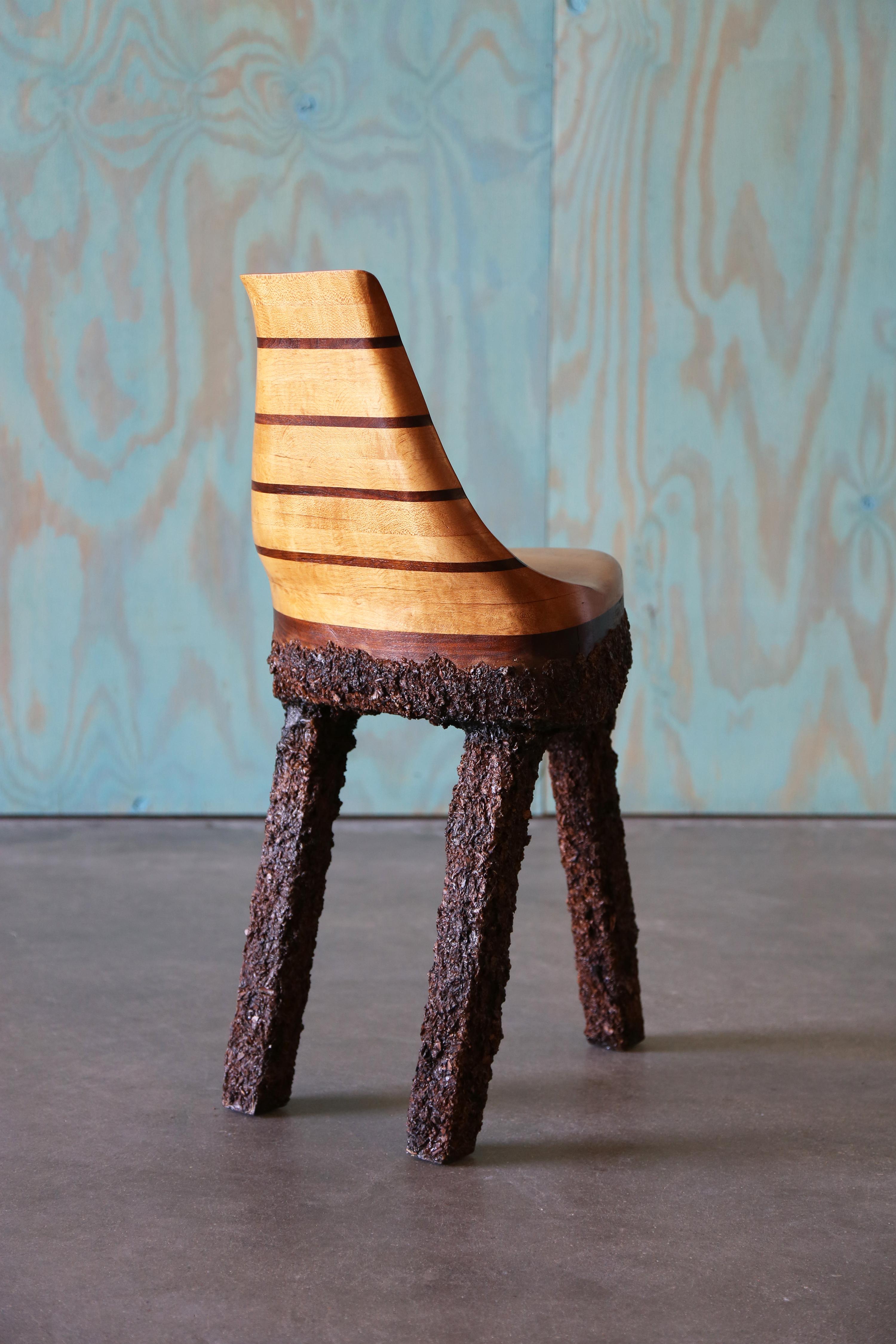 A one of a kind studio craft chair consisting of a solid birch seat, accentuated with solid walnut stripes. Perched on three legs that are bathed in striking wood chips epoxied in place, a very brutalist look which contrasts heavily with the gentle