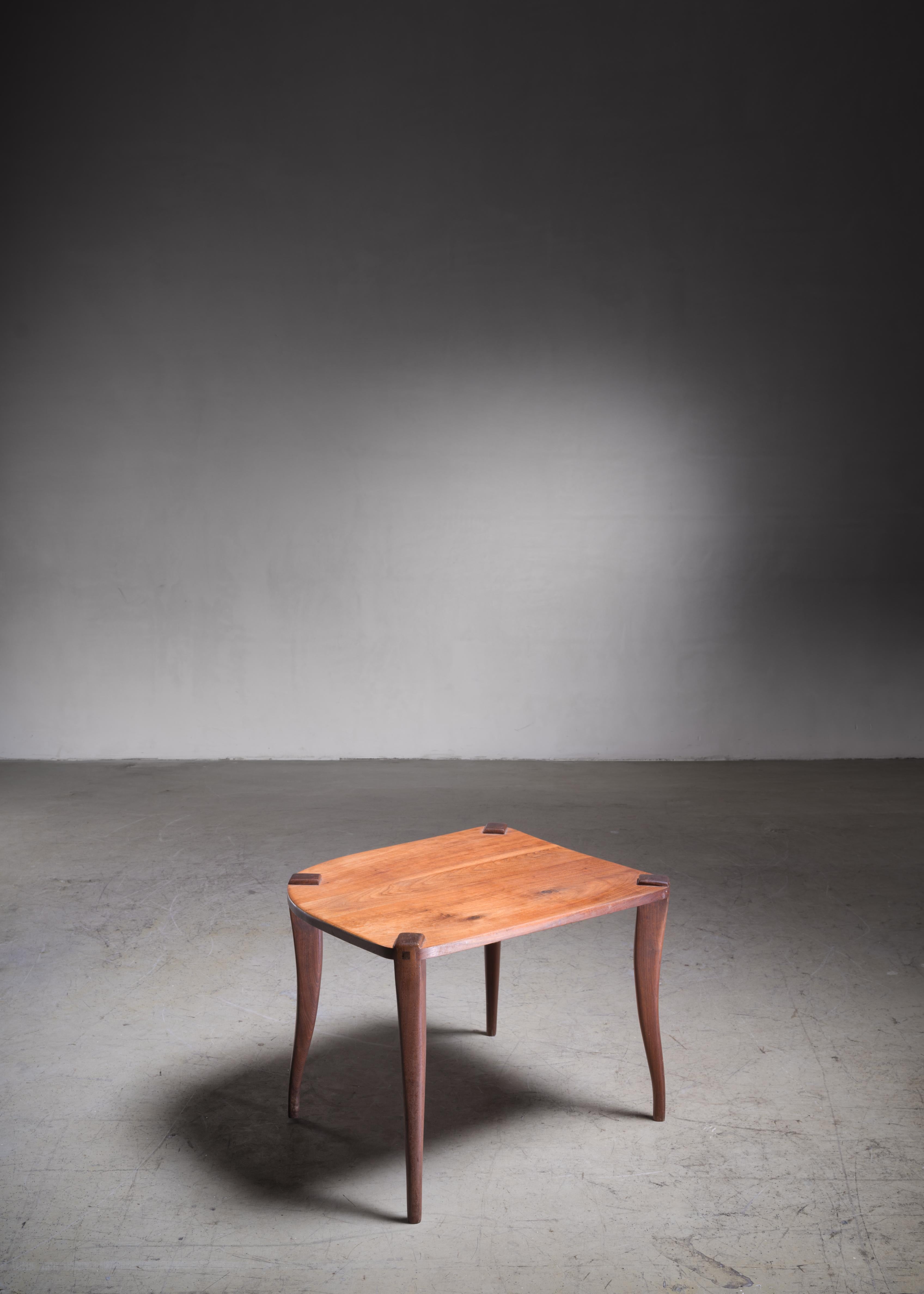 A Mid-Century American studio crafted wooden coffee table with sabre legs and a small swivel drawer.

The combination of the two wood types and the accentuated connection of the legs to the top make this a remarkable piece.
A one of a kind piece