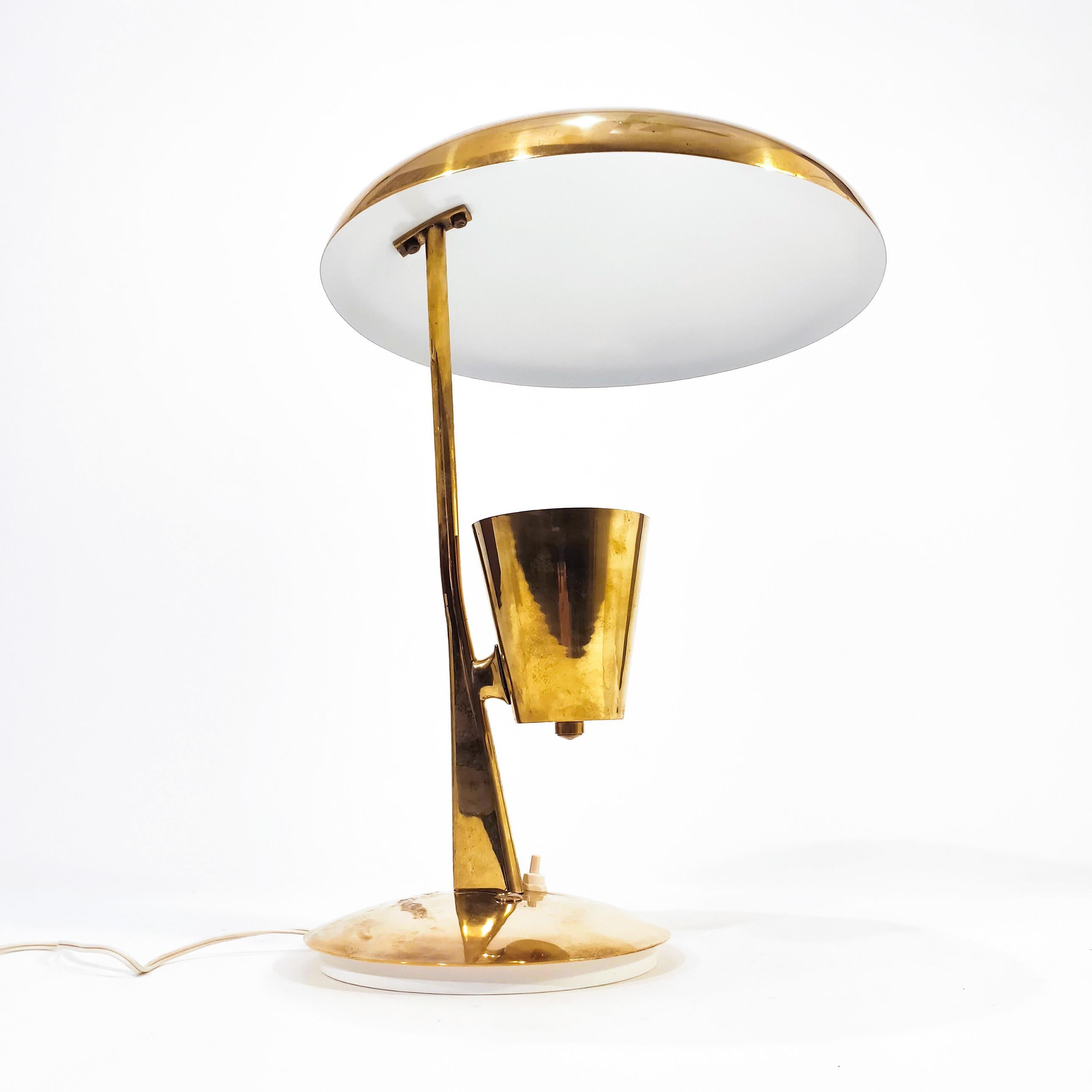 Lampada da tavolo in bronzo dorato massiccio degli anni '50, che ricorda i disegni di Oscar Torlasco per Lumen Milano. Design tipico dell'epoca, con un faretto conico invertito che dirige la luce in un diffusore superiore convesso che la proietta