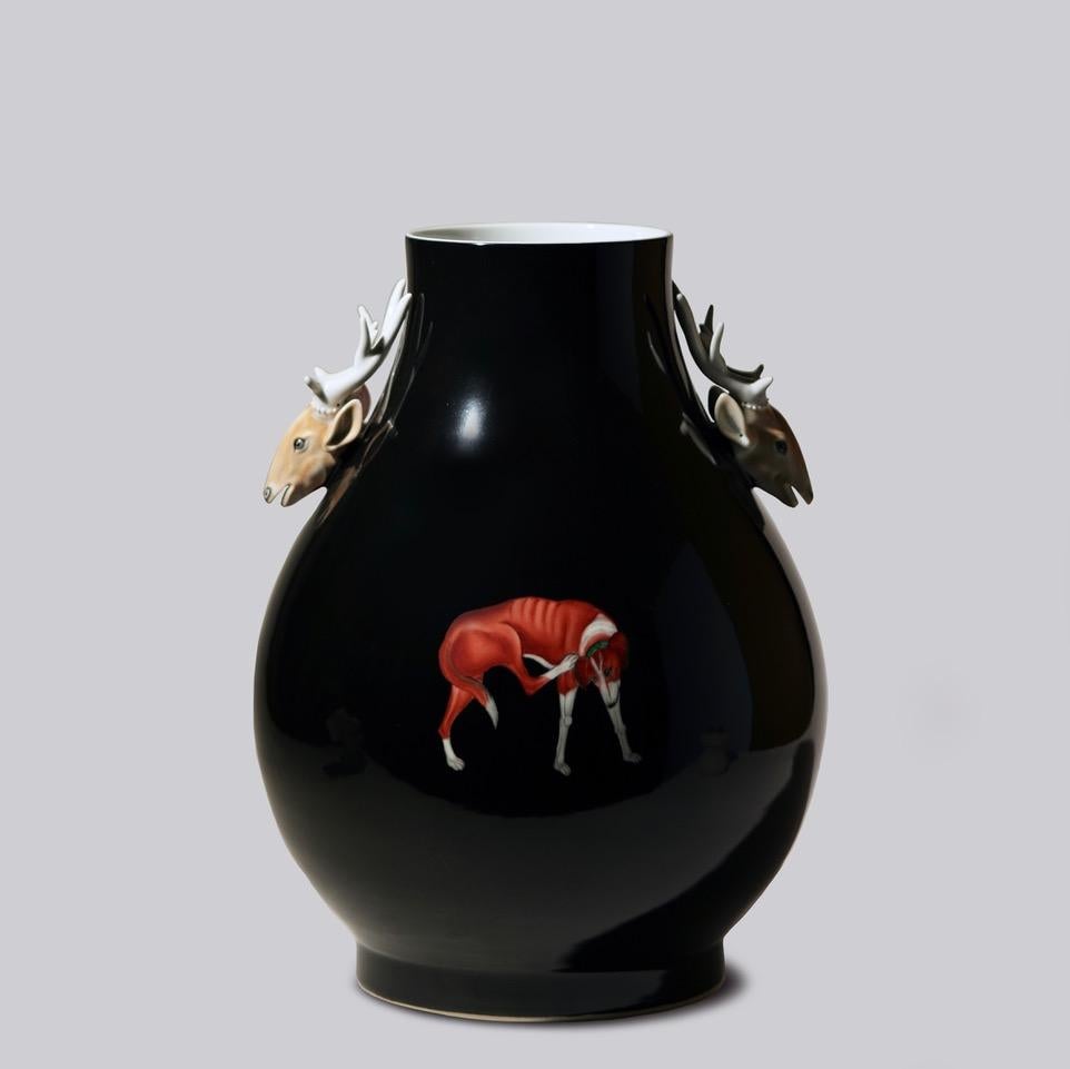 This unique vase is a traditional porcelain vessel from Jingdezhen, a town long distinguished by imperial patronage. This piece is a vintage black vase with molded, sprigged hand painted deer head decorations and a hand painted dog in two poses. The