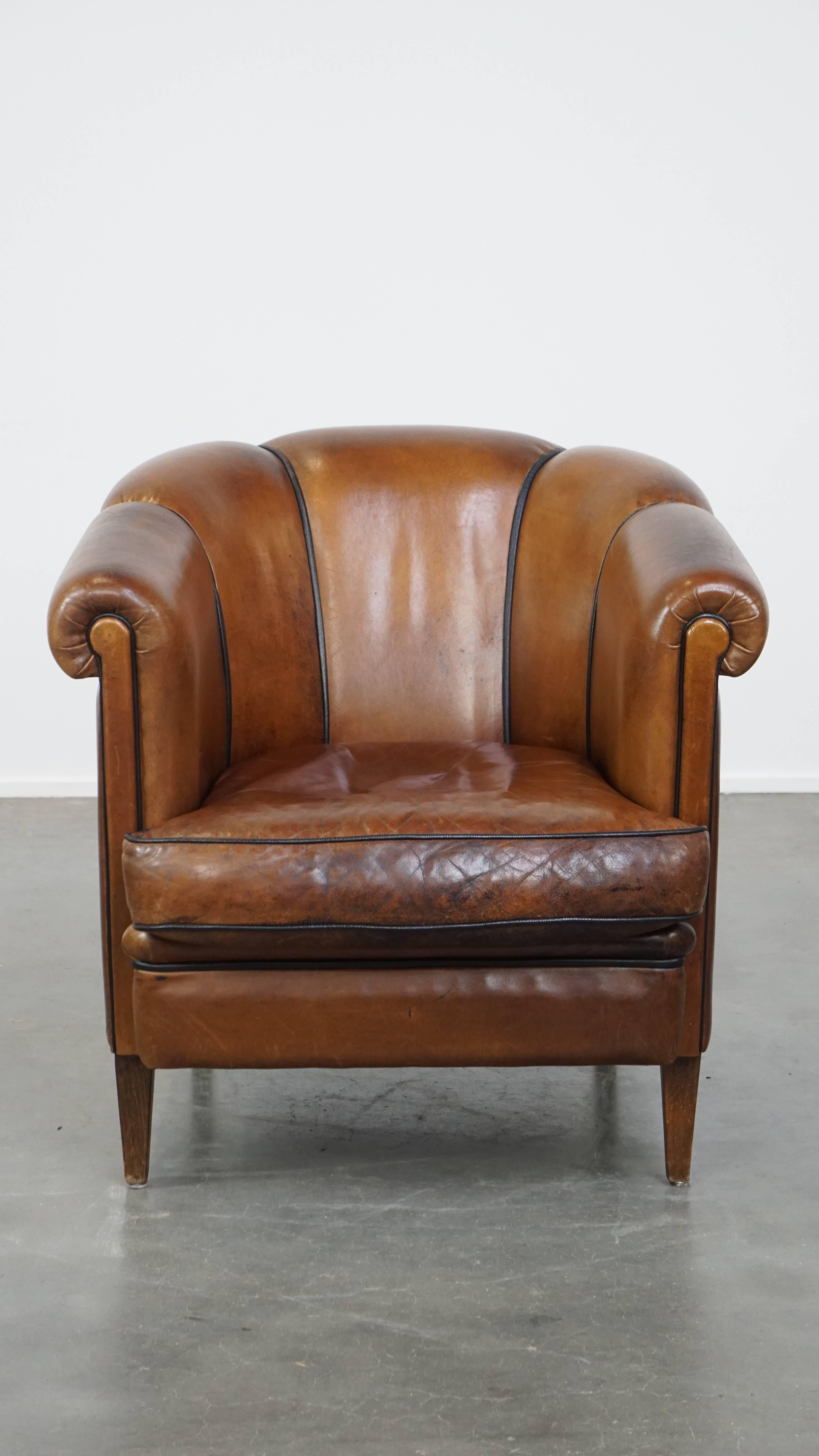 Questa splendida poltrona club in pelle di vacchetta color cognac è un vero e proprio richiamo visivo che si adatta perfettamente a quasi tutti gli interni. La poltrona è rifinita con profili neri e presenta un caratteristico schienale. È dotato di