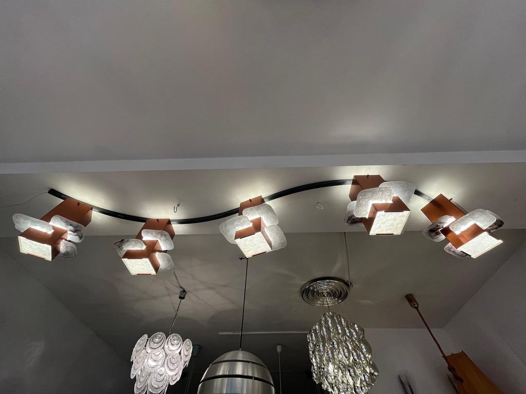 Unique and highly decorative 250 cm long flush mount ceiling lamp, 5 copper square cylinder with nested glass pieces, all 5 fixed on a black steel wavy stem.
Standard bulb E27, compatible with LED bulbs.
Was using at the Grand Theatre of Geneva