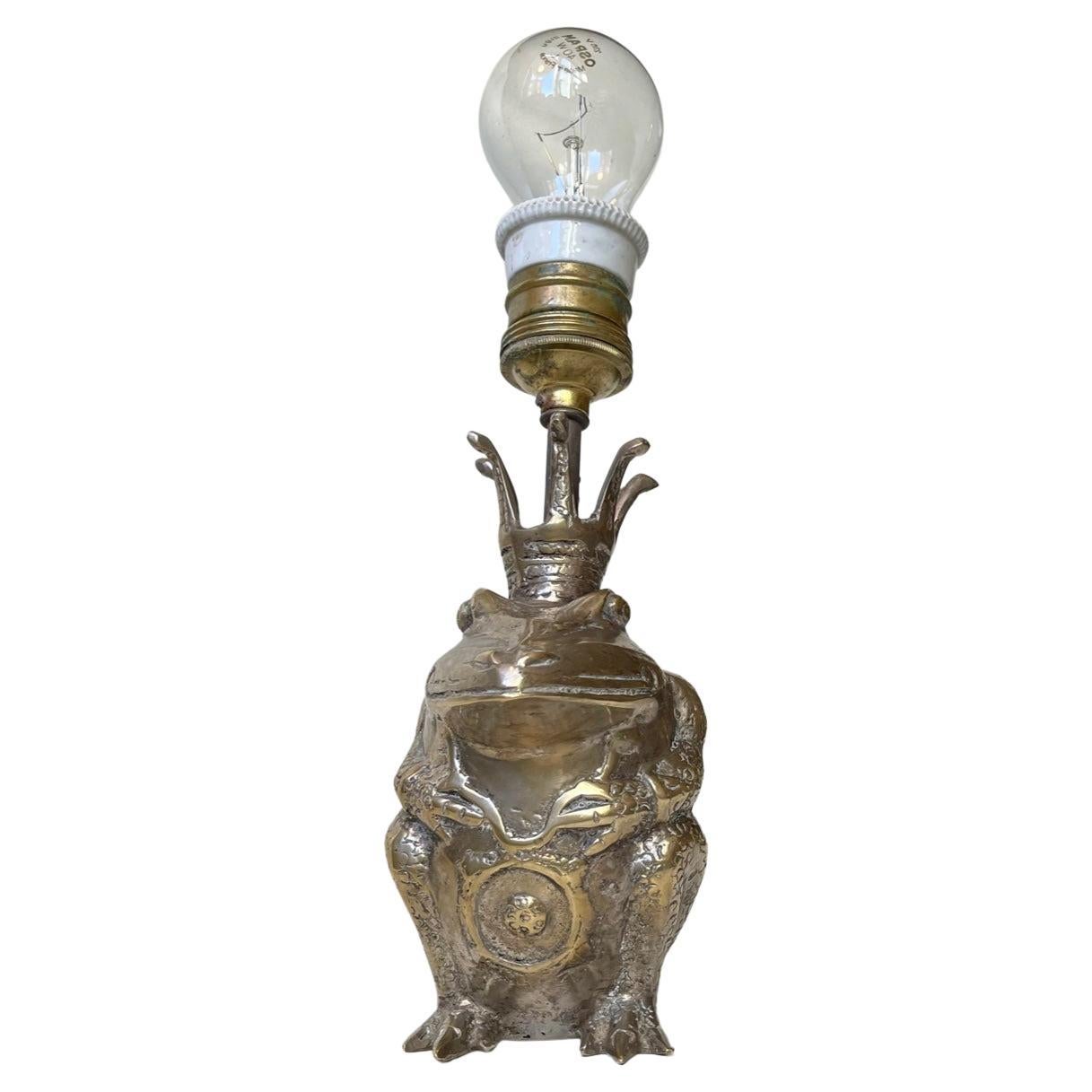 Unusual sculptural table lamp with king toad base. Its made from solid brass and may have been silver plated at some point. We suspect it has been skillfully up-cycled at some point during the 1970s. From a figurine to a table lamp. Measurements: H: