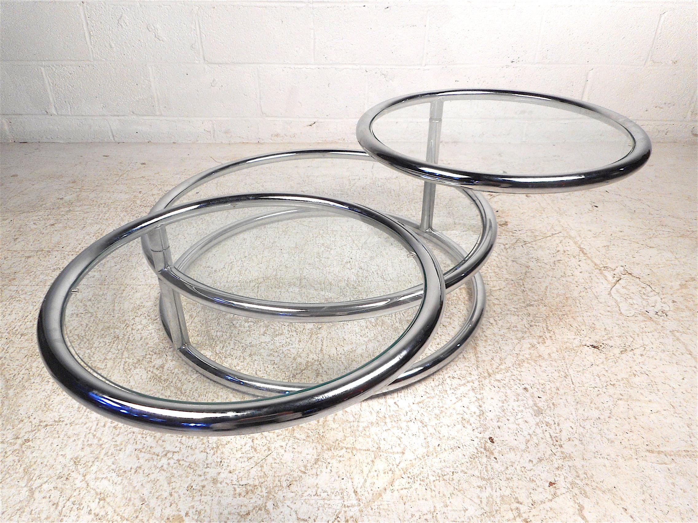 Very unusual vintage modern three-tier coffee/cocktail table. Chrome frame with three circular glass inserts which serve as tabletops. The two smaller tiers swivel allowing for an increased table surface. Interesting addition to any modern interior.