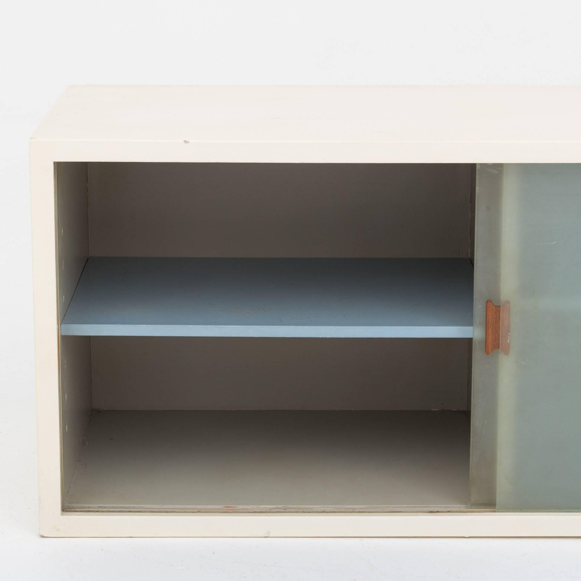 Cabinet in white painted mahogany with frosted glass doors and teak grip. Designed in 1949. Maker Niels Vodder.
