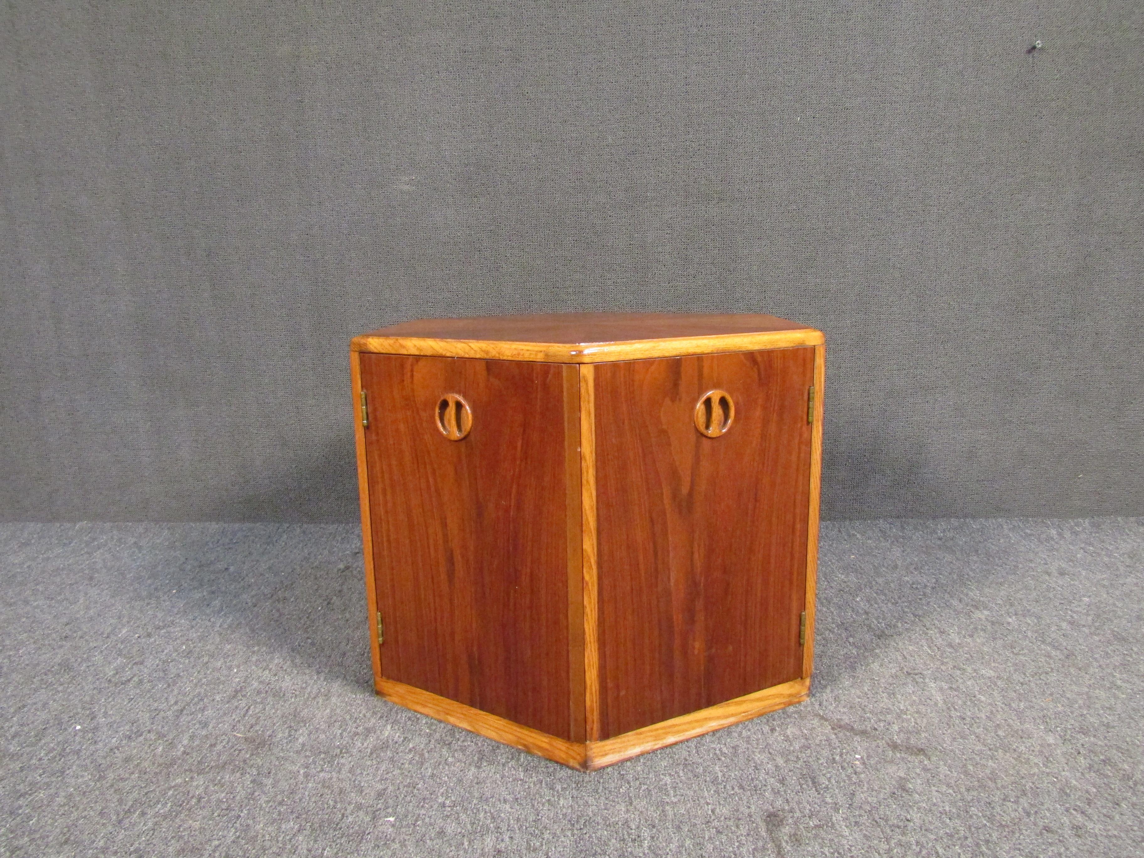With a unique hexagonal design, contrasting woodgrain patterns on its top, sculpted door pulls, and generous storage inside, this vintage walnut side table is a Mid-Century Modern gem. Please confirm item location with seller (NY/NJ).