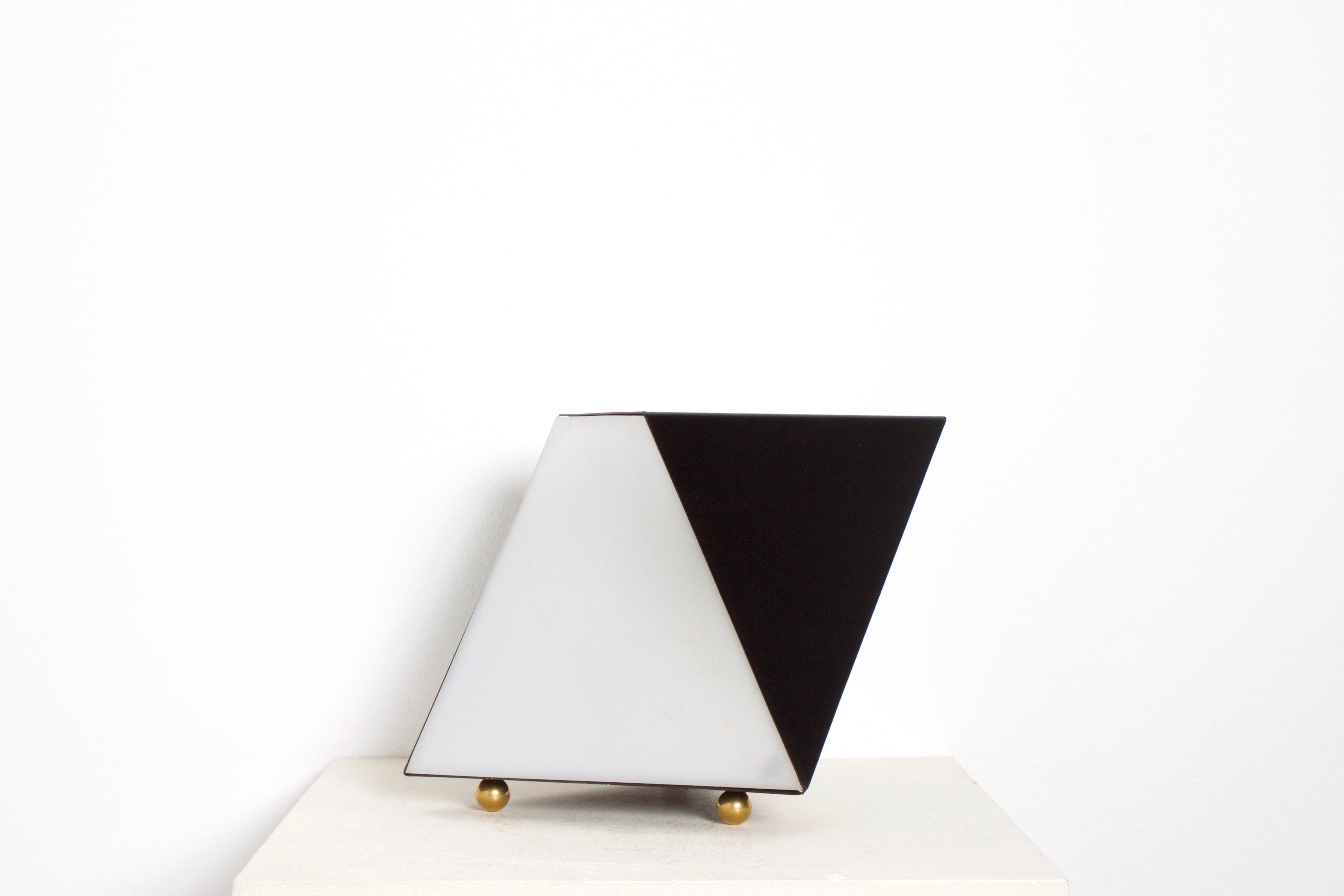 Black and white table lamp by RAAK Amsterdam in very good condition.

The lamp consists of black lacquered metal, white curved plexiglass and brass feet.

This lamp looks different from each side and this gives an unique effect. 

Keywords: