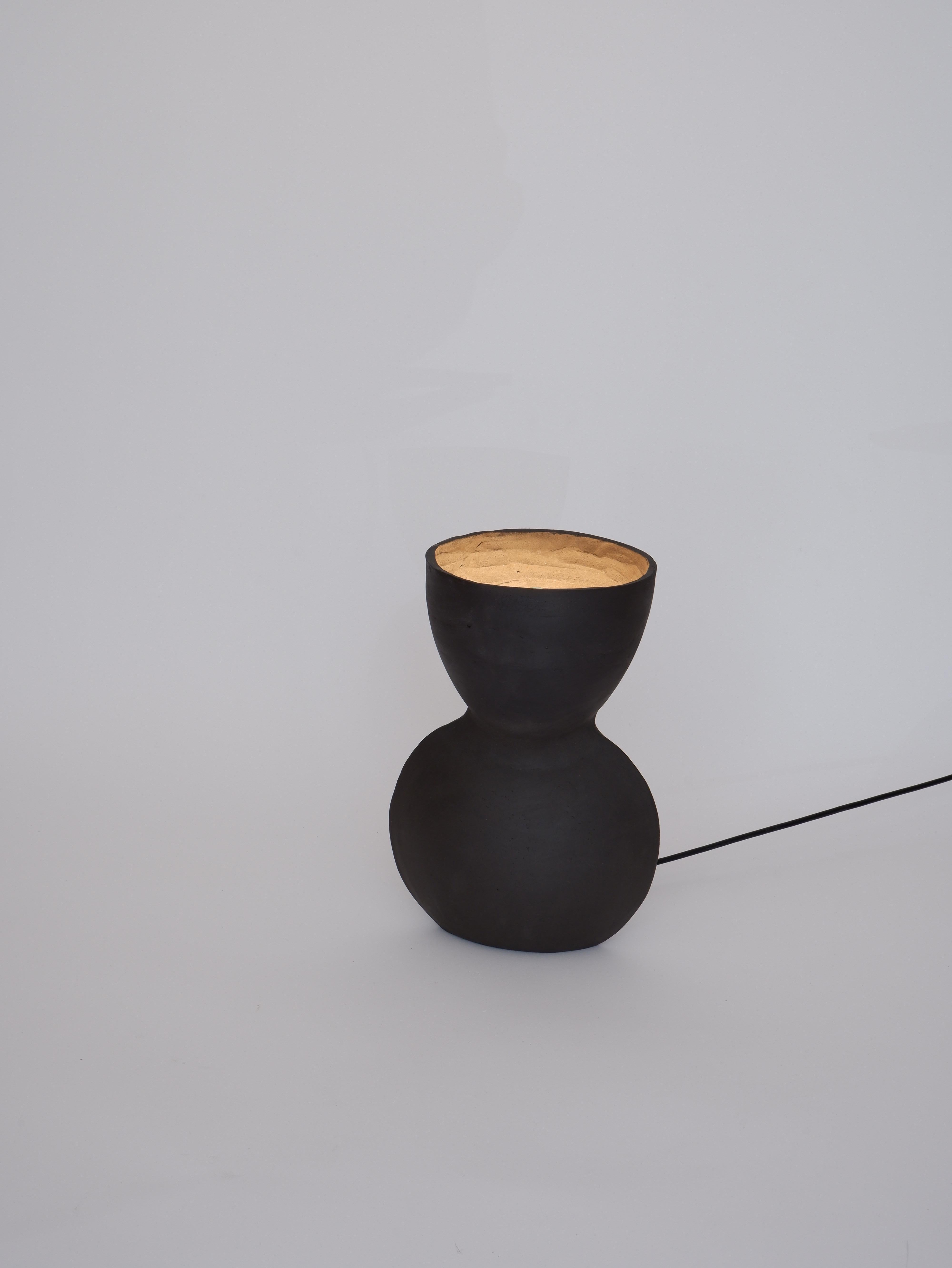 Unira Small Black Lamp by Ia Kutateladze
One Of A Kind.
Dimensions: D 14 x W 18 x H 25 cm.
Materials: Clay.

Each piece is one of a kind, due to its free hand-building process. Different color variations available: raw black clay, raw white clay and