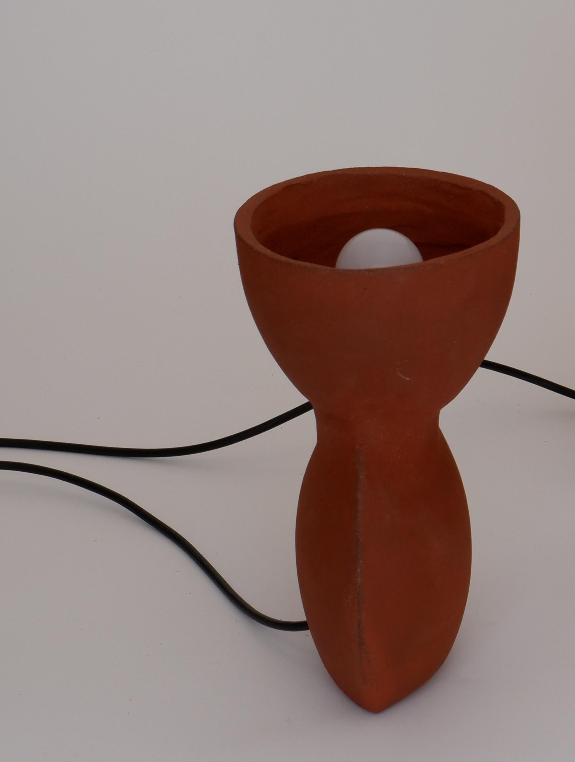 Unira Small Red Lamp by Ia Kutateladze
One Of A Kind.
Dimensions: D 14 x W 18 x H 25 cm.
Materials: Clay.

Each piece is one of a kind, due to its free hand-building process. Different color variations available: raw black clay, raw white clay and