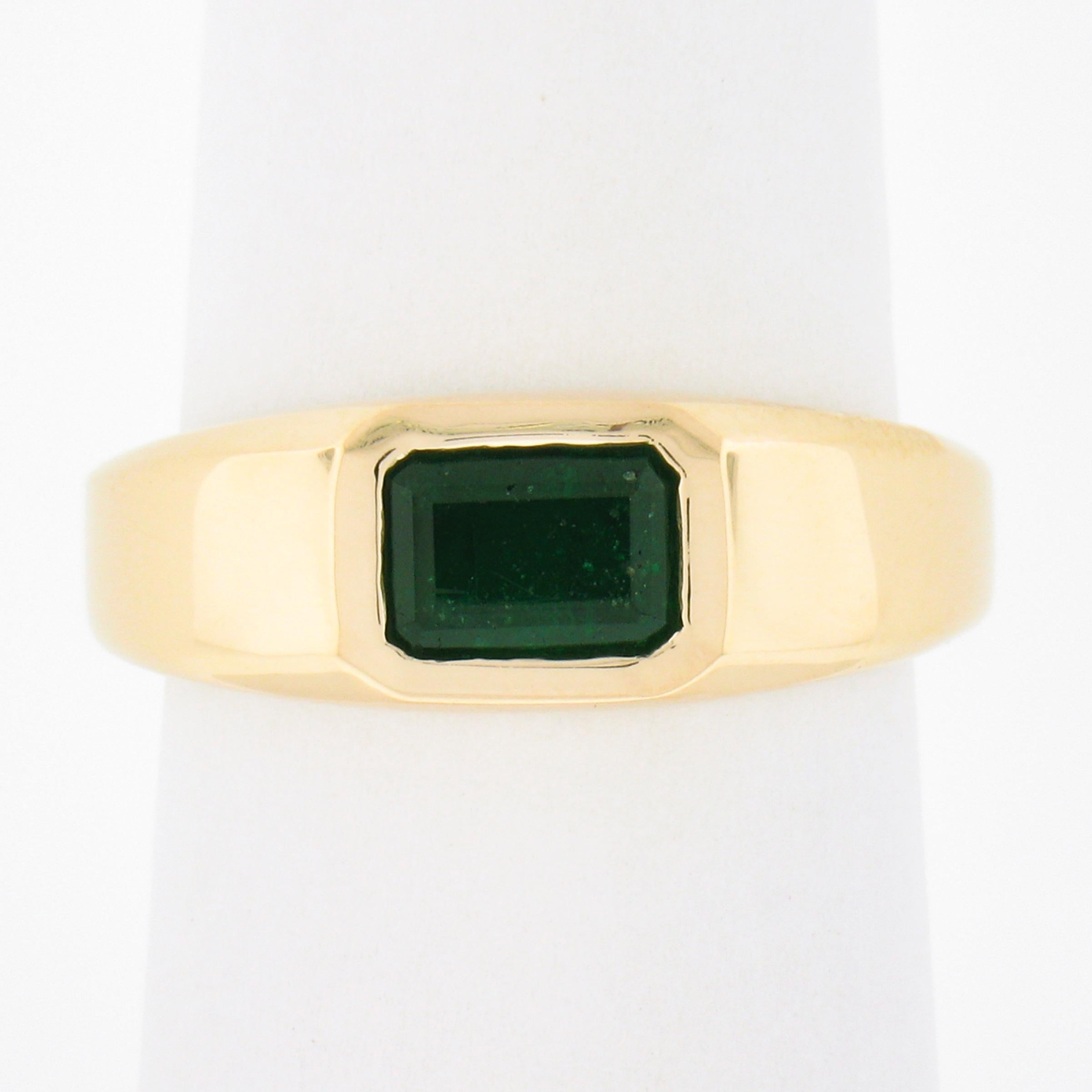 Here we have a simple, yet absolutely gorgeous, emerald solitaire ring that is newly crafted from solid 14k yellow gold. The solitaire is a nice deep green, elongated emerald cut natural genuine emerald stone and is neatly bezel set sideways at the