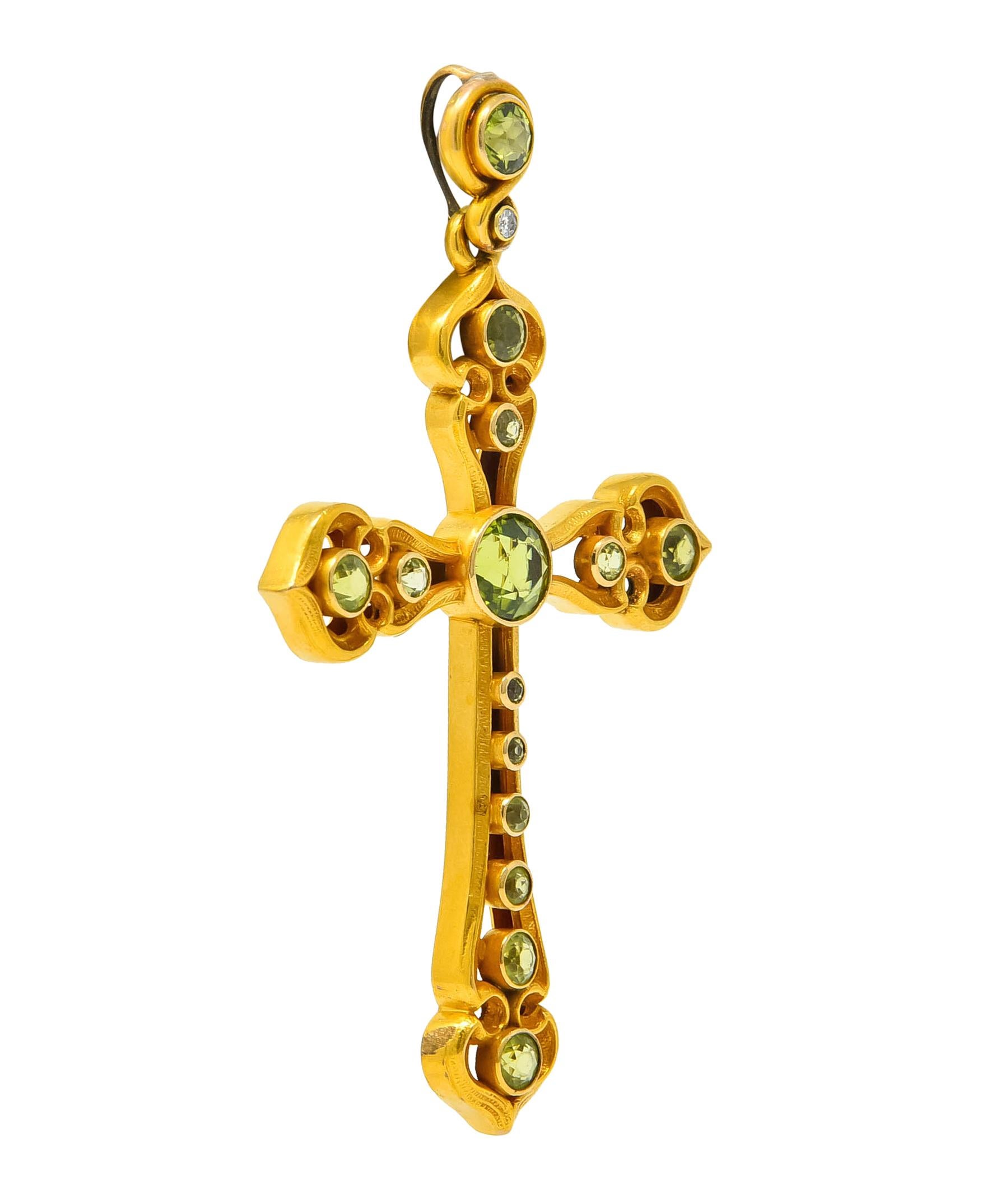 Pendant designed as a large openwork cross comprised of an intricate celtic style with a matte gold finish

Cross and bale bezel set throughout by round cut peridot, varying in size, transparent and very light yellowish-green to a saturated