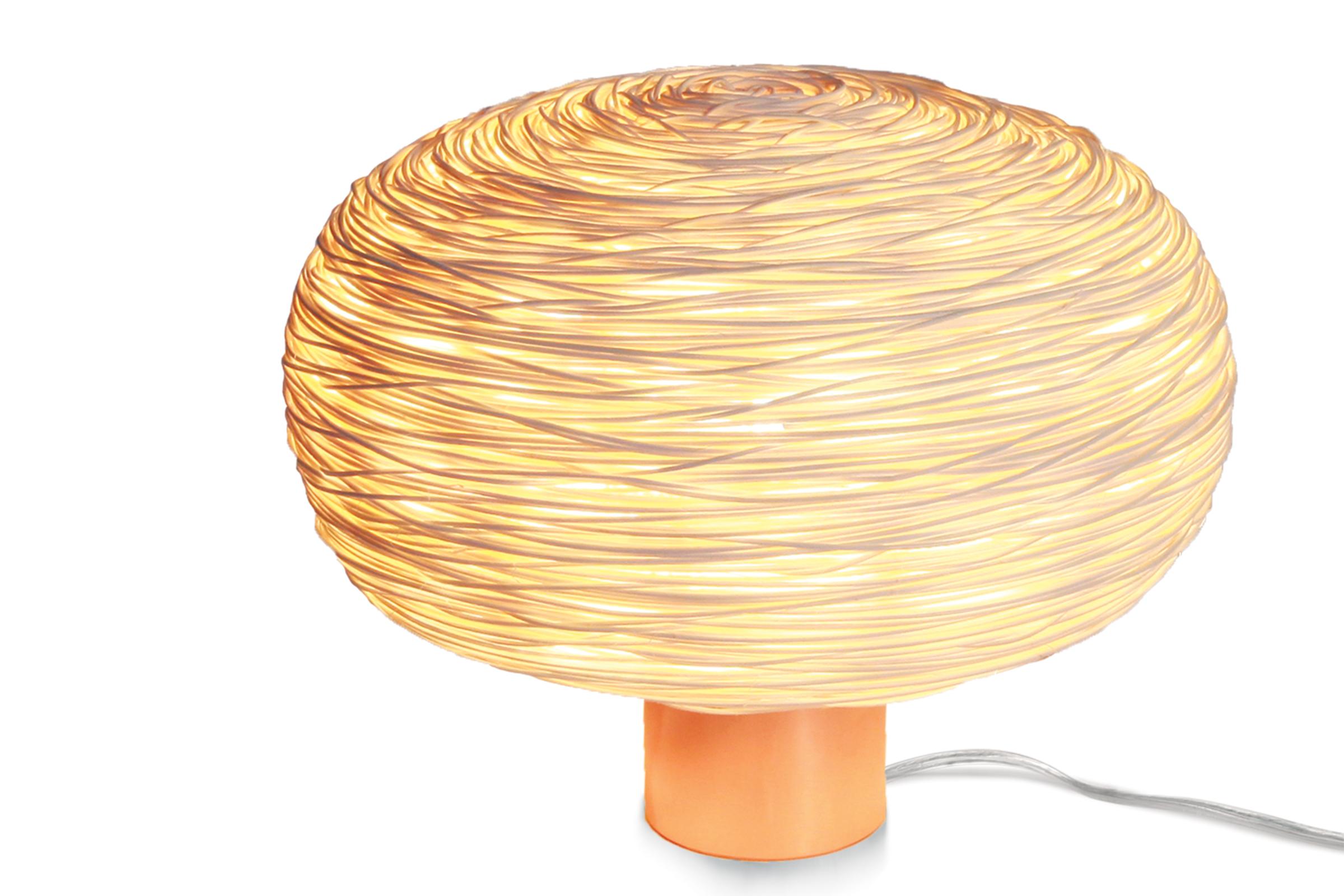 Unit (table-R) is rattan hand-woven table light where the structure evokes a flattened sphere or mini world. The structure is then clad with around one kilometre of superfine 1 mm. rattan wire in a random weave developed by Ango. When used in such a