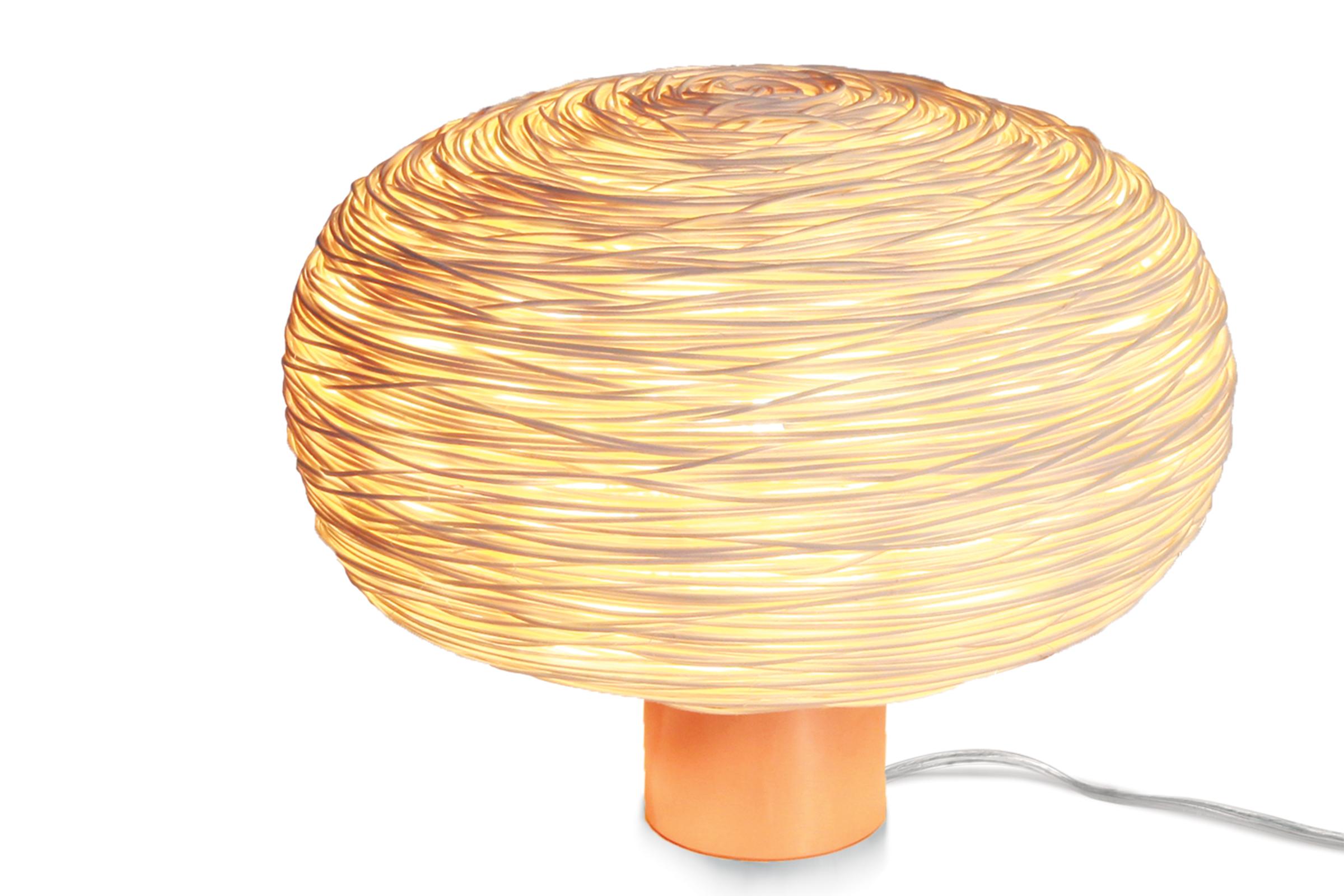Unit (table-R) è una lampada da tavolo in rattan la cui struttura evoca una sfera appiattita o un mini mondo. La struttura viene poi rivestita con circa un chilometro di filo di rattan superfine da 1 mm. in una trama casuale sviluppata da Ango. Se