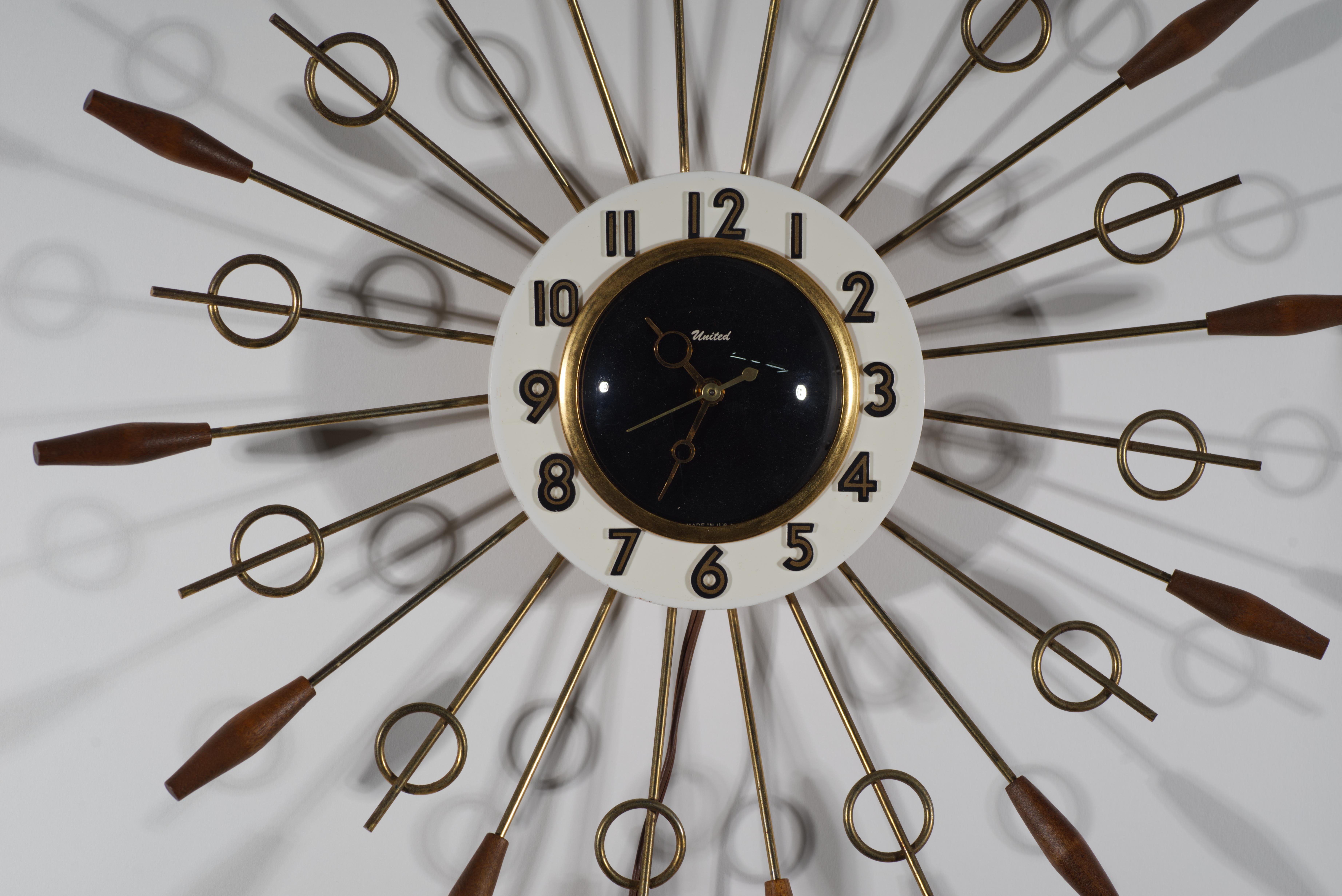 
El reloj de pared vintage de estrella presenta radios de varillas de latón, que irradian hacia fuera desde la esfera central redonda y terminan con puntas alternas de nogal y anillos de latón. Está equipado con un movimiento de horas, minutos y