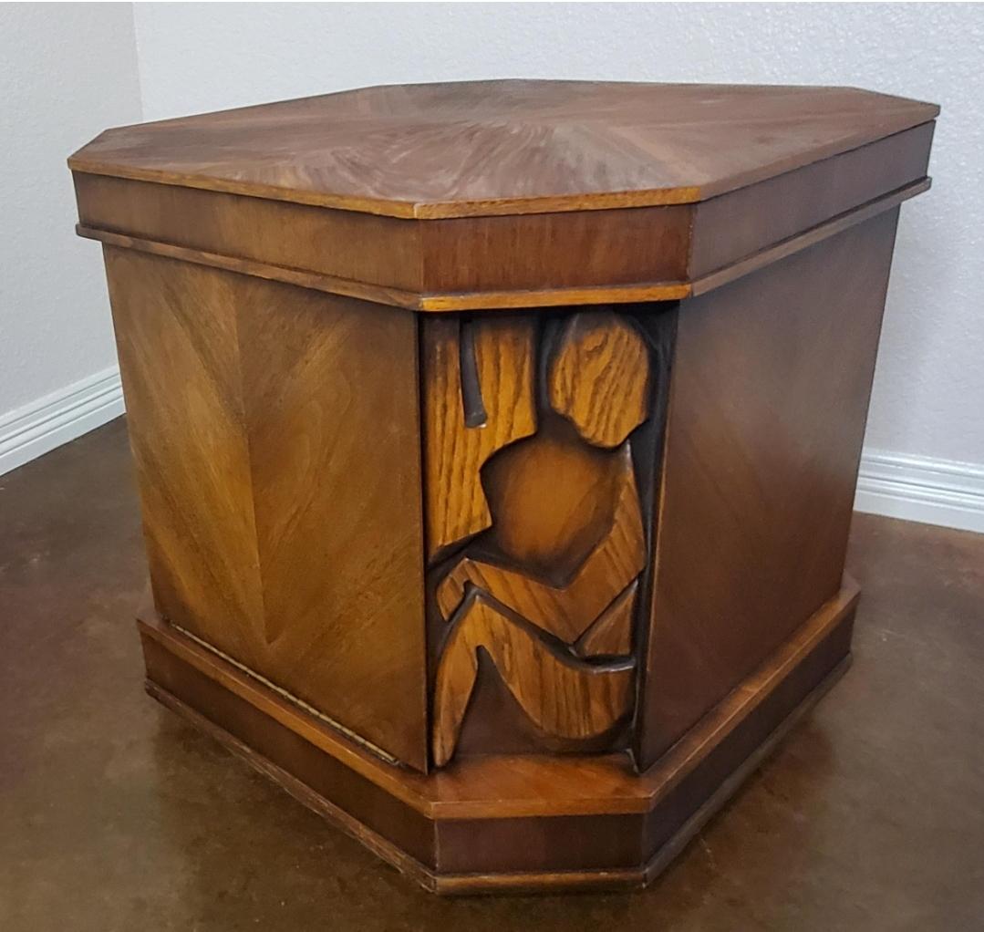 Rare 1960s United Furniture Tiki Line brutalist nightstand/ end table. 
Carvings on all 4 corners.
One side has a drawbridge/ door.
Solid wood.
No veneers. 
Will add warmth and character to any room.

Sits flat on the floor, is sitting on a mini
