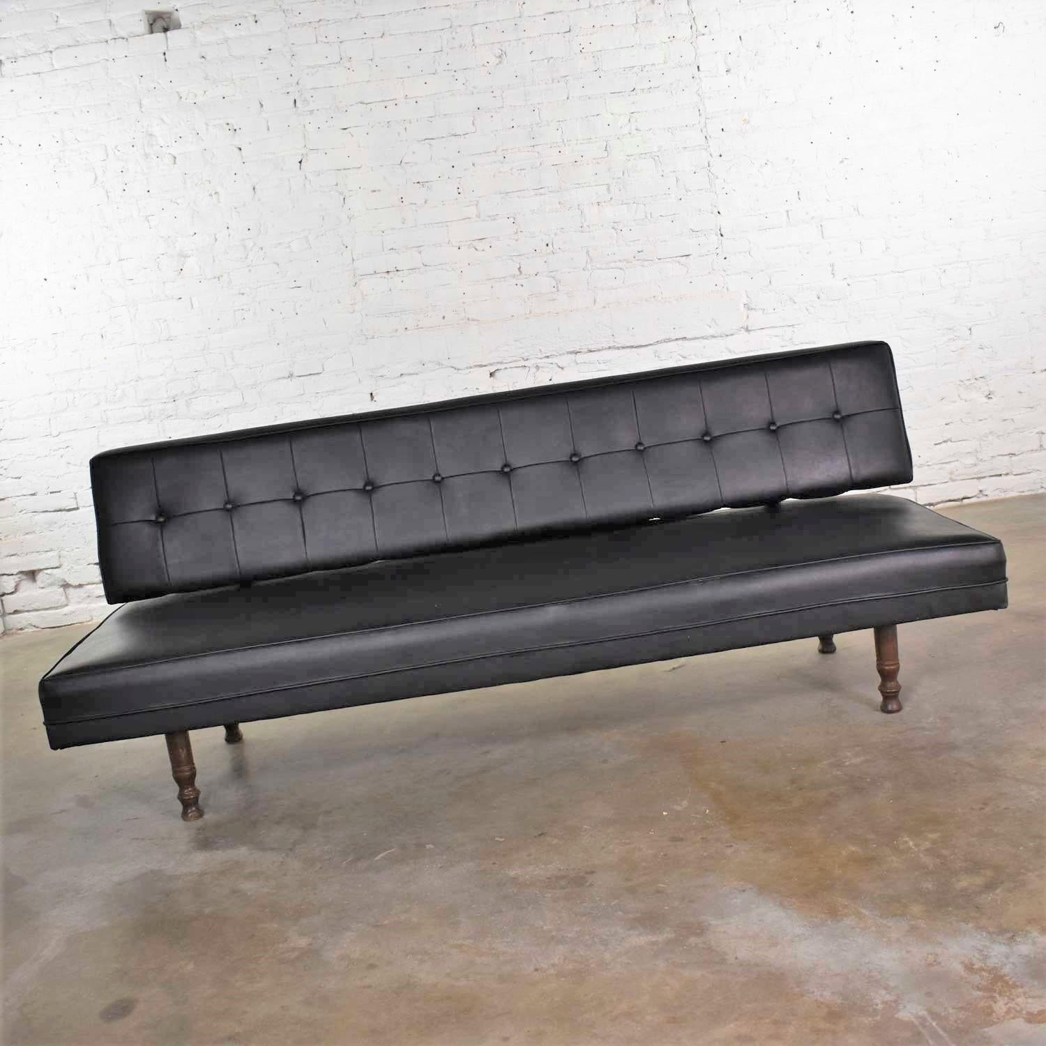 Handsome Mid-Century Modern settee or loveseat sofa in black vinyl faux leather by Universal of High Point. It is in wonderful vintage condition. We have restored the wood, cleaned the vinyl, repaired a few spots where stitching was loose, and put