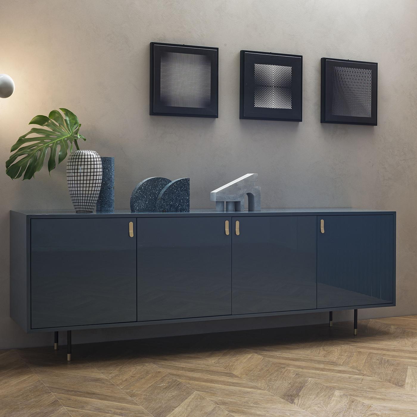 Questa credenza è una superba sintesi tra minimalismo e glamour, proposta in un'elegante laccatura blu denim lucida. Le sottili gambe cilindriche con dettagli in ottone fanno parte della robusta struttura in metallo brunito, che offre un generoso