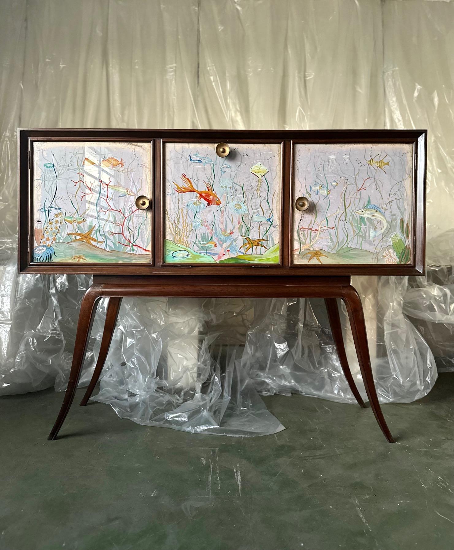 A classic and, at the same time, original sideboard featuring one of a kind underwater themed panels. The paintings showcase the deep sea full of animals and algae over a blue background. This thematic extends over all three drawers with beautiful