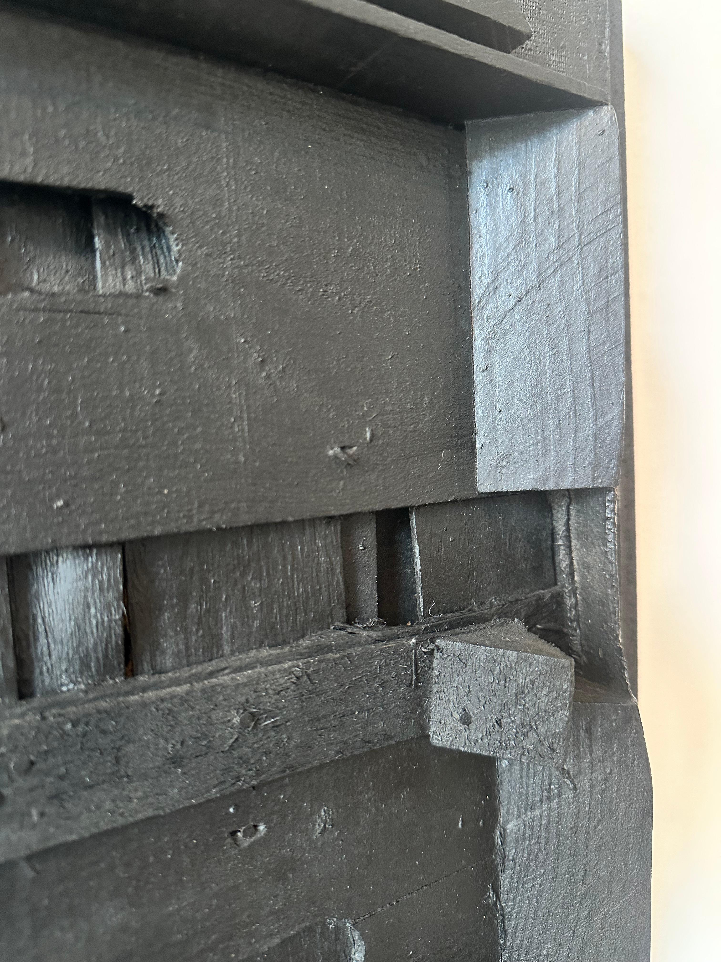 This unique black wooden assemblage from 1951 is a captivating example of mid-century post-war abstract relief art. Signed with an illegible signature, the piece carries a mysterious allure that invites the viewer to explore abstraction,