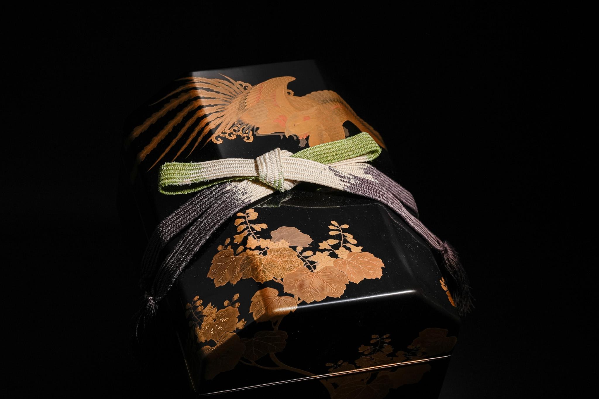 This Edo-period drum box features a black lacquer ground decorated with gold maki-e. A majestic phoenix spreads its wings across the lid, its long tail flowing in elegant arcs while each feather is rendered with refined detail and subtle shading.