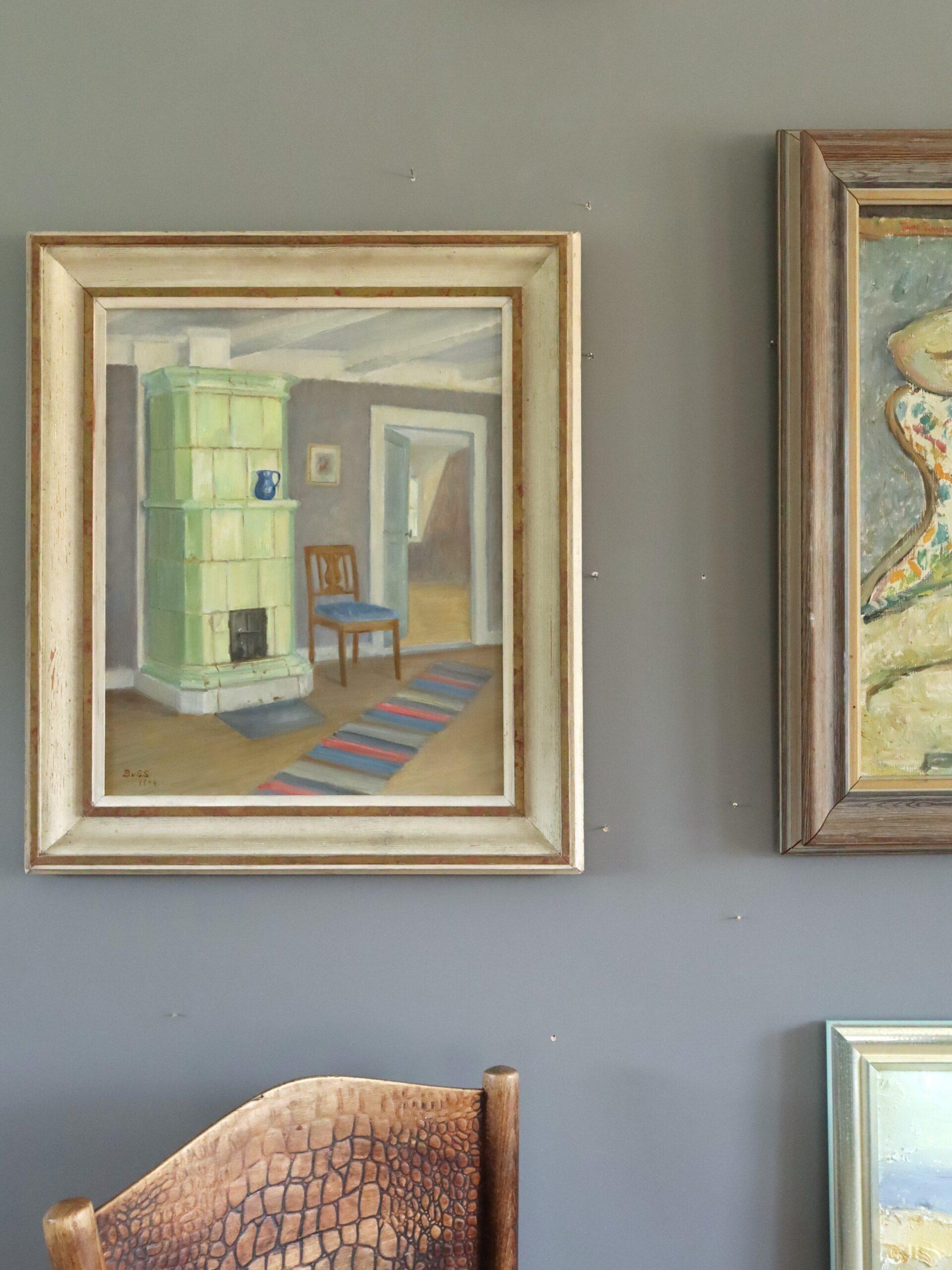 INTERIOR WITH GREEN STOVE
Size: 59 x 51 cm (including frame)
Oil on canvas

A serene mid-century interior scene that captures a quiet moment in a Scandinavian home, painted in oil onto canvas and dated 1944.

The composition is anchored by a pale
