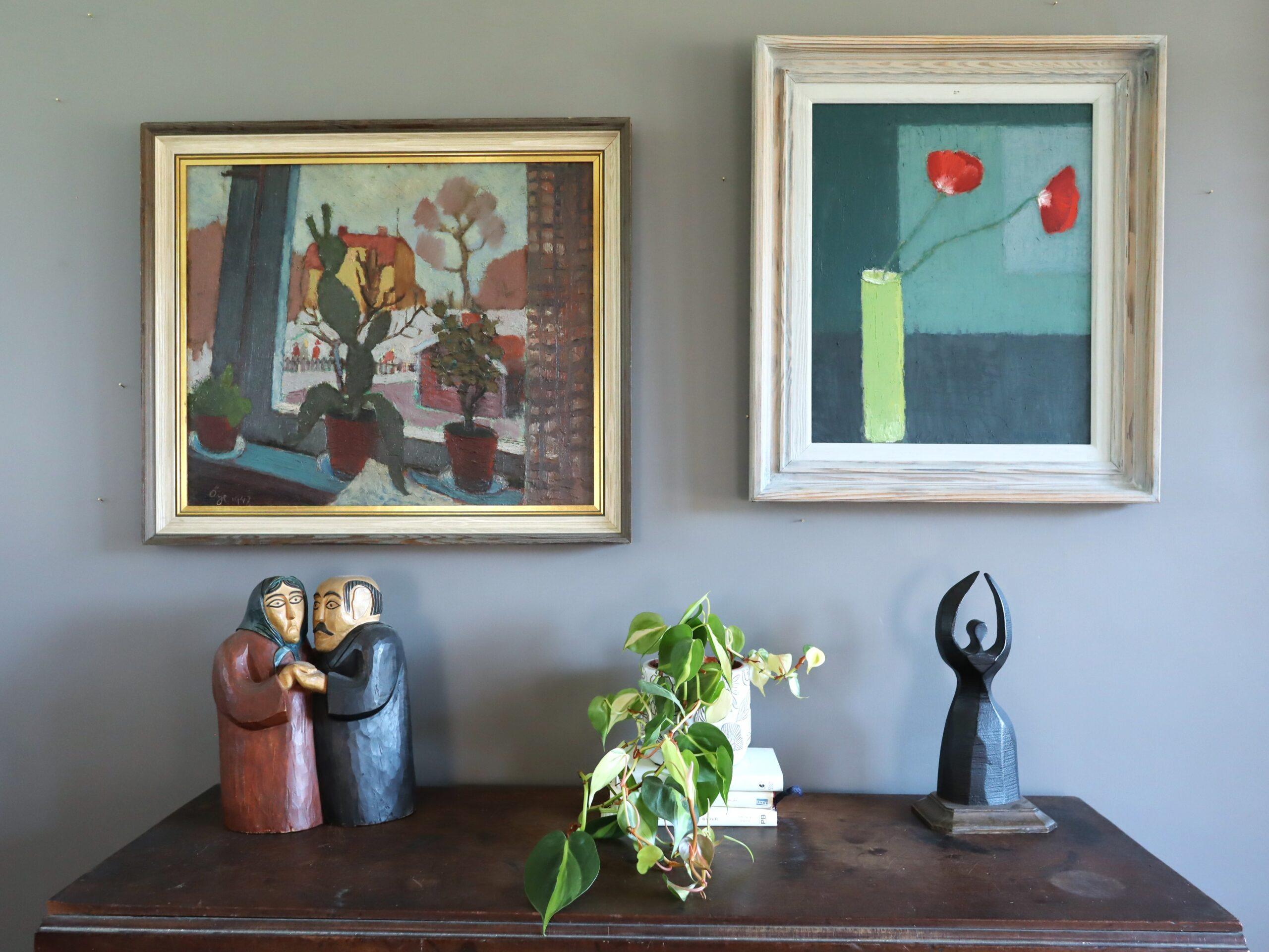 CACTI BY THE WINDOW
Size: 55 x 64 cm (including frame)
Oil on board

An elegant mid-century still life that captures a charming scene of three potted plants arranged along a windowsill and silhouetted against an exterior scene of houses, executed in