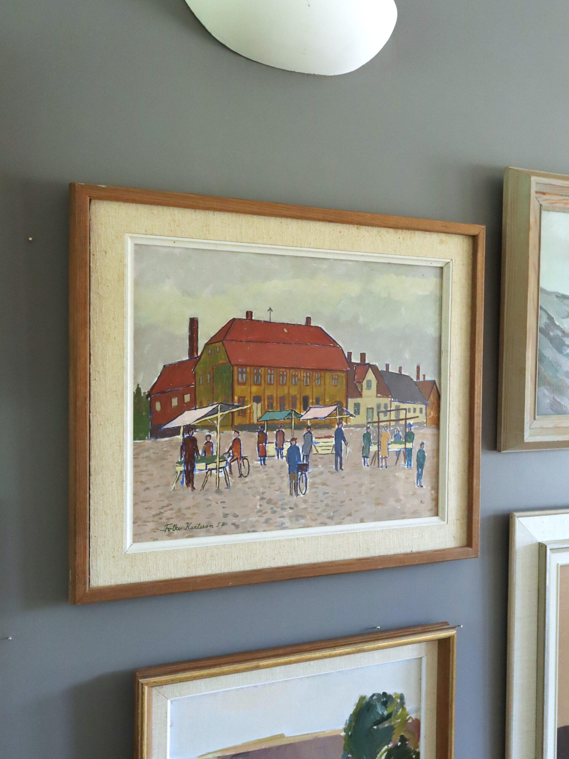 MARKTTAG AUF DEM MARKTPLATZ
Größe: 50,5 x 58,5 cm (einschließlich Rahmen)
Öl auf Karton

Eine charmante Straßenszene aus der Mitte des Jahrhunderts im naiven Stil, die den Rhythmus und die Wärme eines europäischen Marktplatzes am Markttag einfängt,