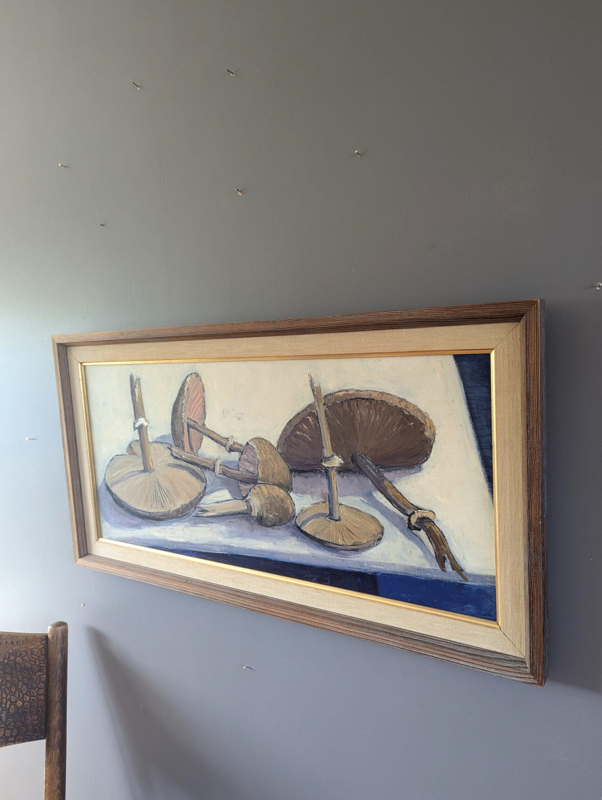 STILLLEBEN MIT PILZEN
Größe: 37,5 x 72,5 cm (einschließlich Rahmen)
Öl auf Karton

Ein ruhiges und detailliertes Stillleben aus der Mitte des Jahrhunderts, das in Öl auf Karton ausgeführt und 1957 datiert wurde.

Das Gemälde zeigt eine Reihe von