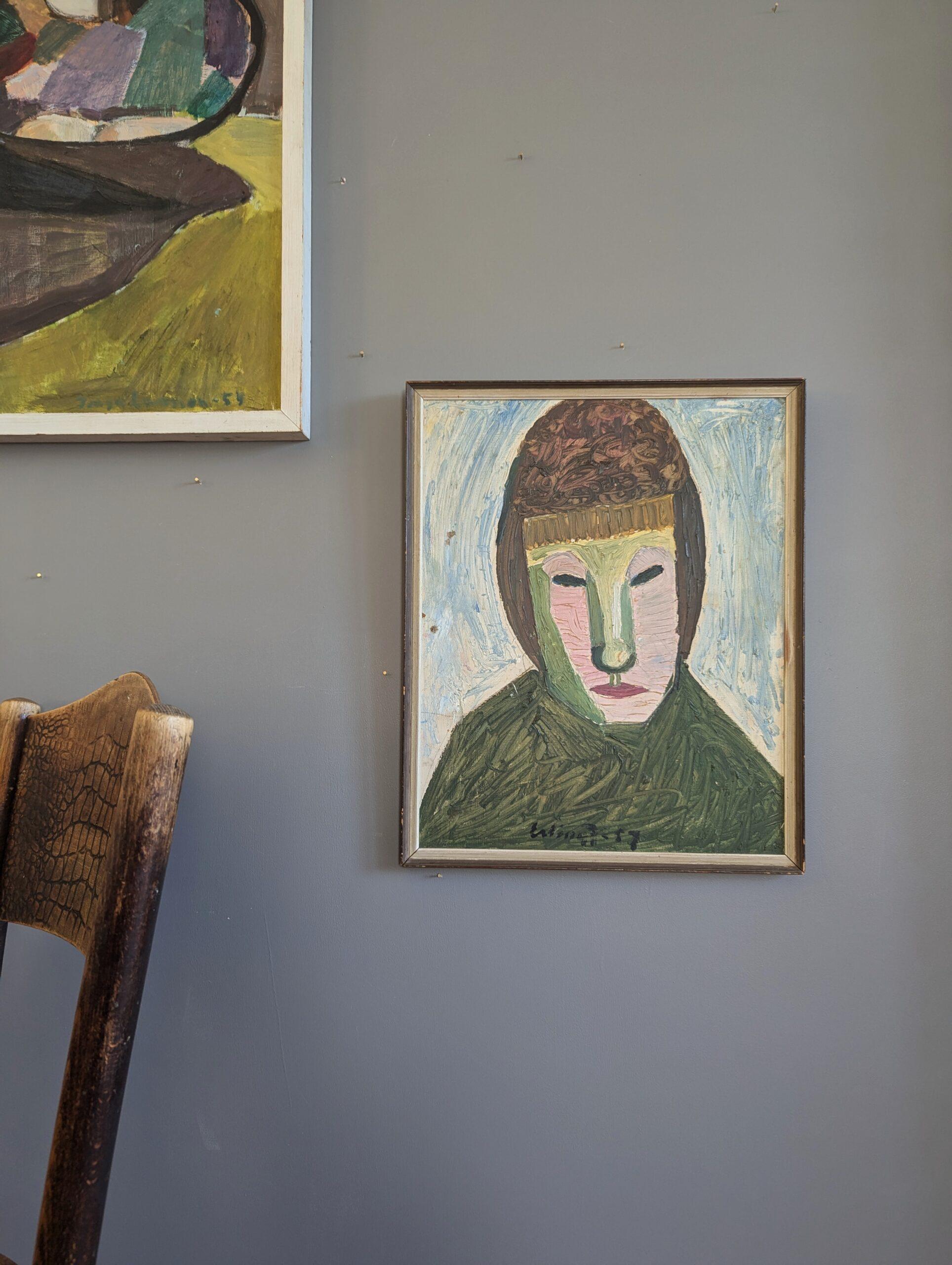 BEHIND THE MASK
Size: 43 x 35 cm (including frame)
Oil on board

A bold and enigmatic mid-century figurative portrait, executed in oil onto board and dated 1957.

The composition depicts a simplified and abstracted figure with a frontal, mask-like