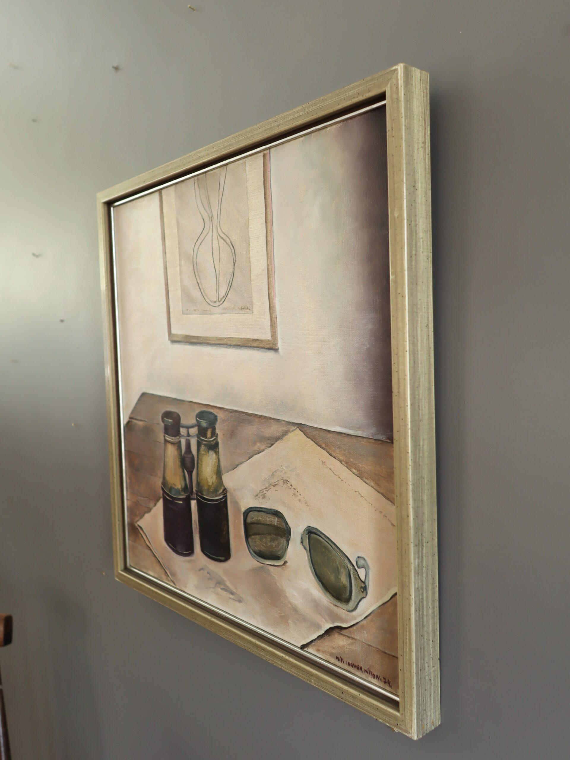 NATURA MORTA CON BINOCOLO
Dimensioni: 45 x 44 cm (cornice inclusa)
Olio su tela

Un'intima natura morta d'interni che presenta un tranquillo tableau di oggetti quotidiani, resi in un sobrio ma evocativo stile modernista, eseguito a olio su tela e