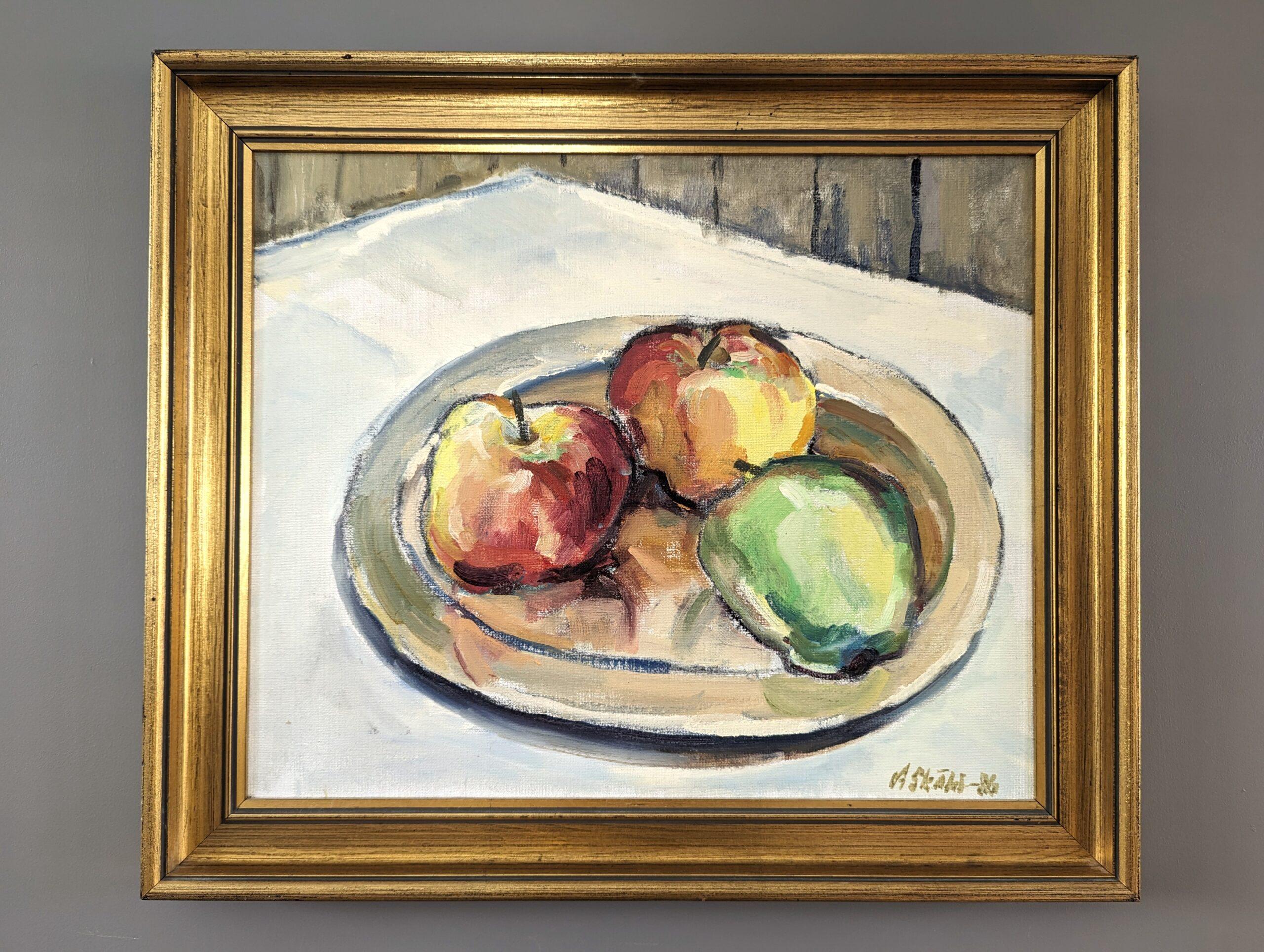 ORCHARD APPLES
Size: 46.5 x 54.5 cm (including frame)
Oil on Canvas

A very skilfully executed modernist still life composition in oil, painted onto canvas and dated 1986.

In this picture, 3 apples sit on a saucer on a white surface, with  a