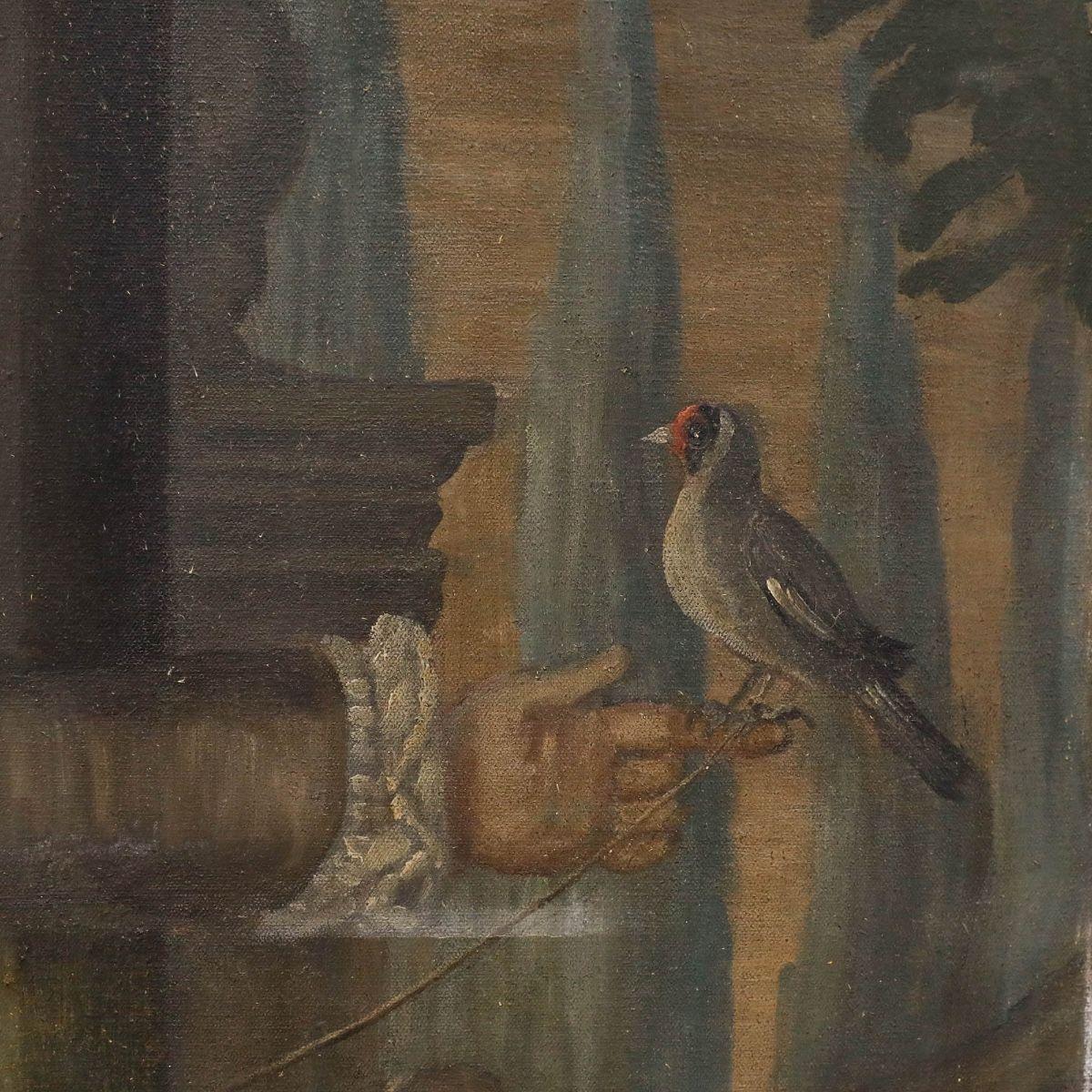 This charming 20th-century portrait depicts a young boy in elegant period attire, wearing a brown coat over a vibrant red waistcoat and matching red stockings, with a songbird in hand. The composition features classical architectural elements,