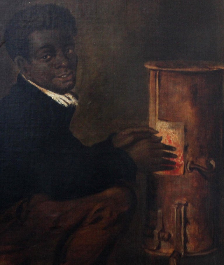 This interesting interior portrait oil painting is from the 19th century American School. The painting is of a black boy warming his hands in front of a stove. He is sat and on a barrel and bellows and coals lay on the floor beside him. Although he