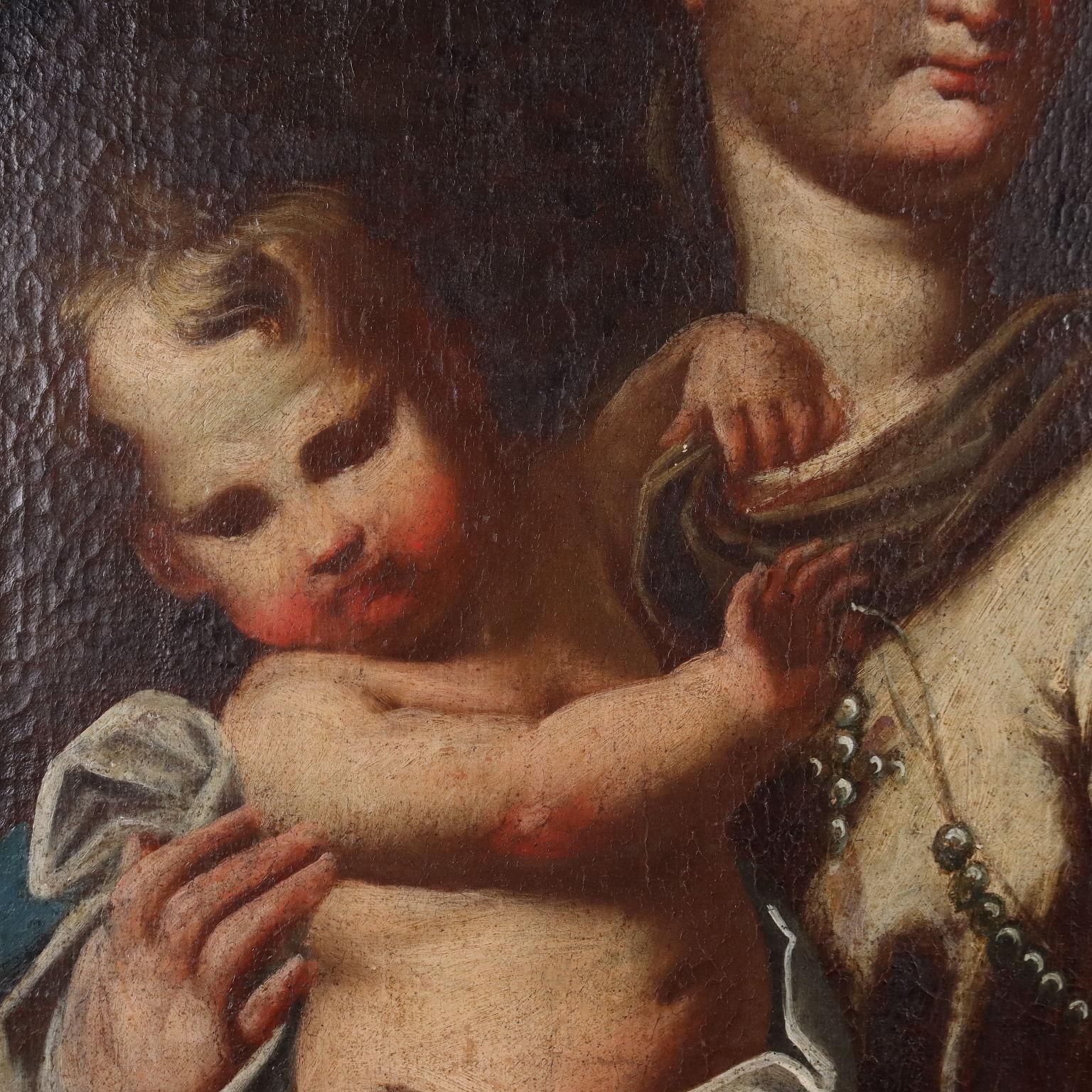 Olio su tela.
La Madonna tiene in braccio il Bambin Gesù, ed entrambi sorreggono la corona del Rosario, invito alla devozione mariana. In alto, dai cieli aperti si affacciano angeli.
Il dipinto è stato precedentemente restaurato e ritelato; qualche